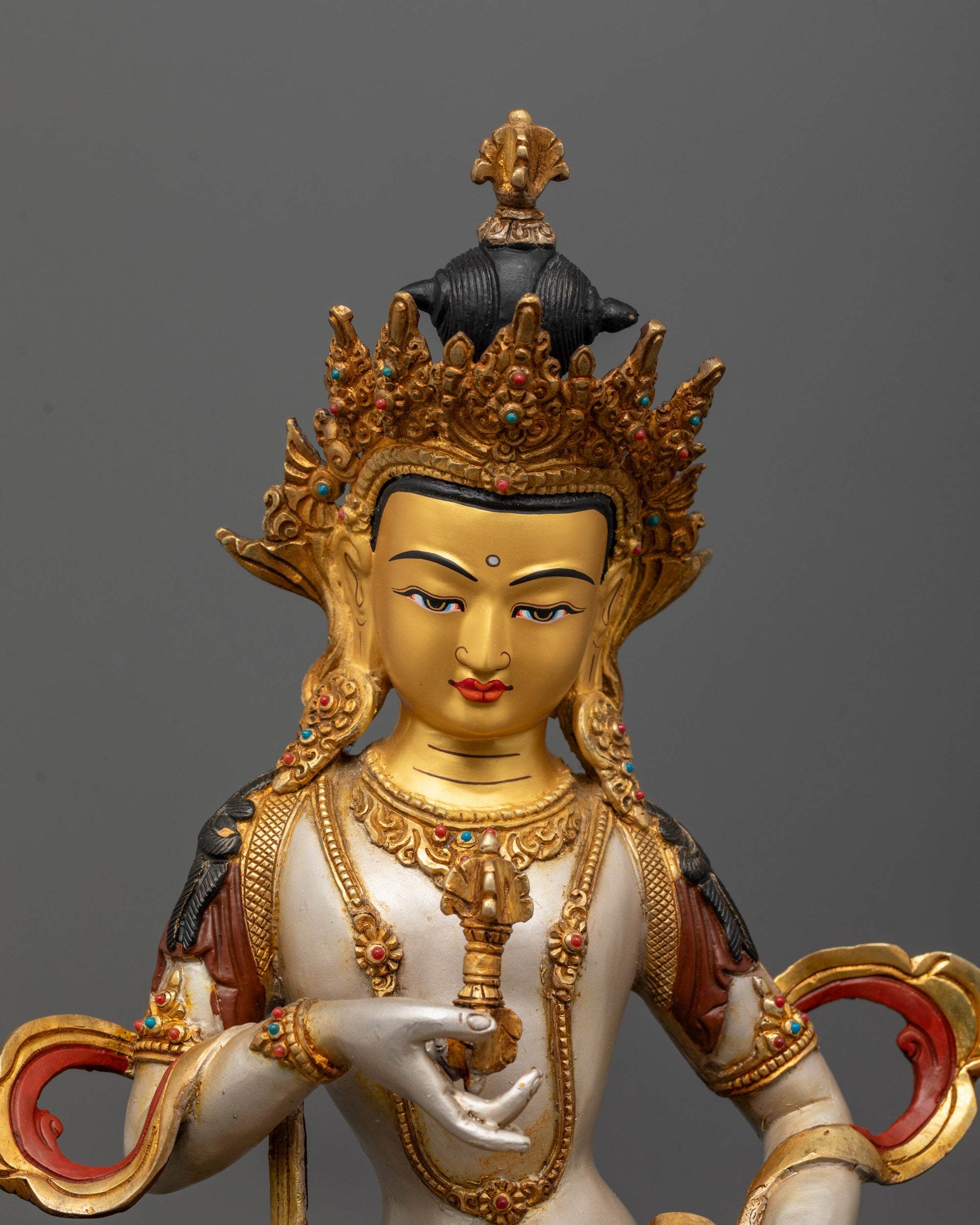 Close-up of Vajrasattva holding vajra and bell in meditation pose with semi-precious stone