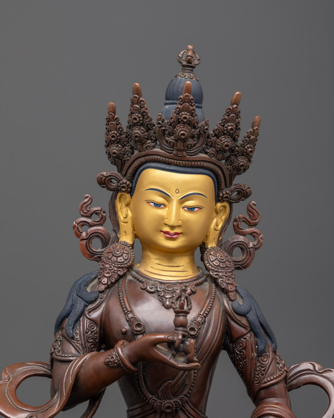 Close-up of Vajrasattva statue’s detailed oxidized copper body with gold gilding and intricate craftsmanship.