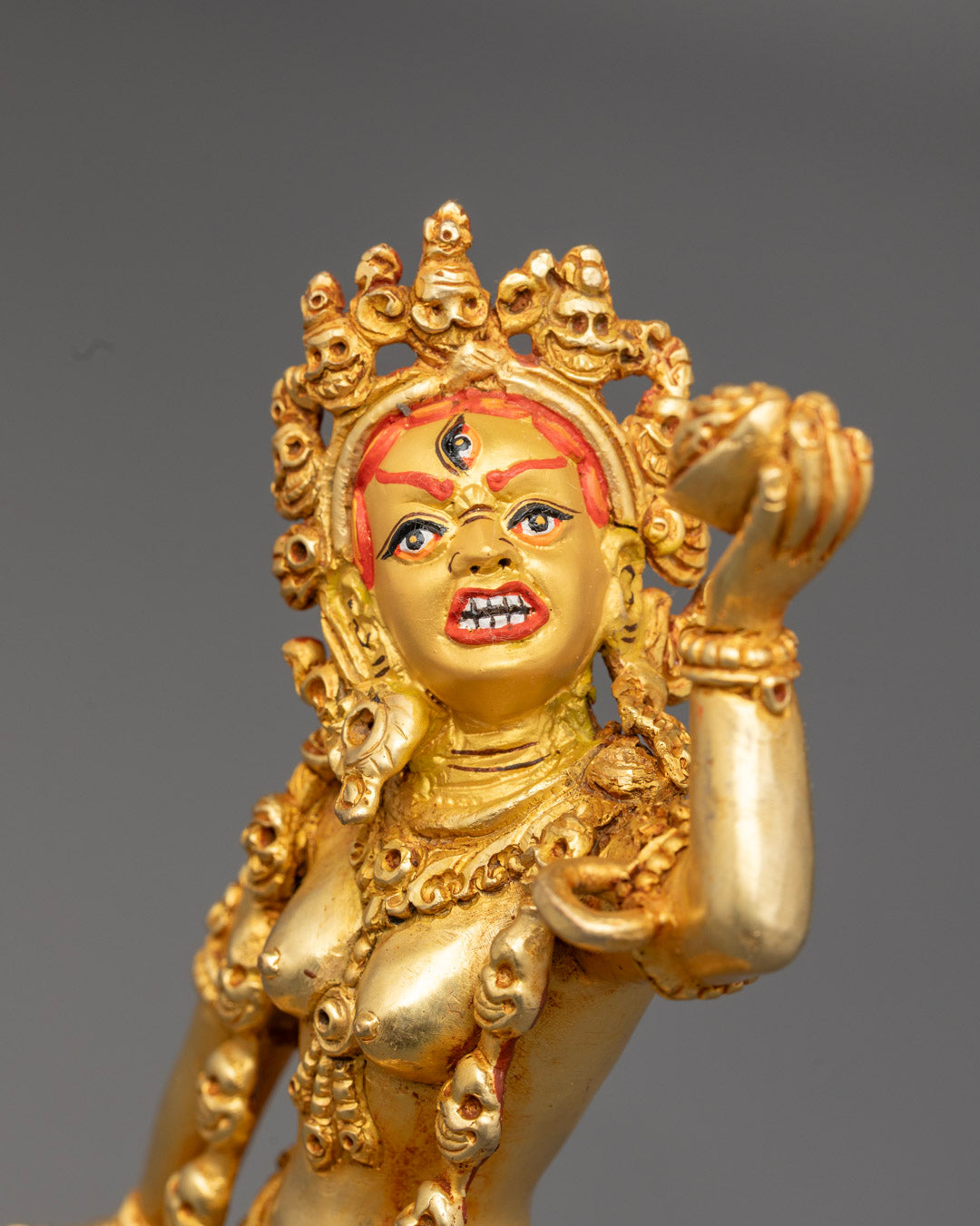 Vajrayogini’s fierce expression, adorned with semi-precious stones and symbolic ornaments.