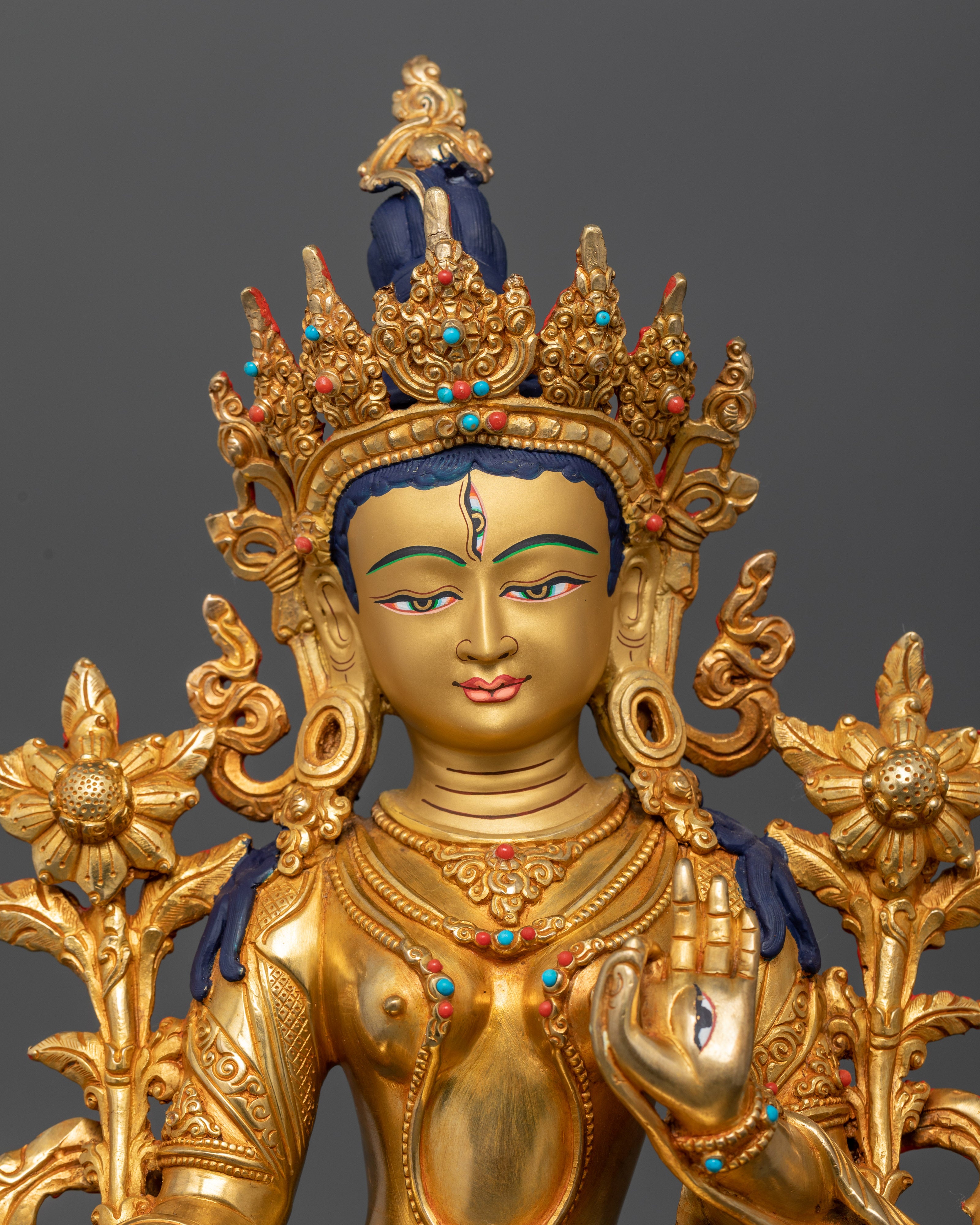 Close-up of White Tara Bodhisattva with seven eyes and jeweled crown in copper sculpture
