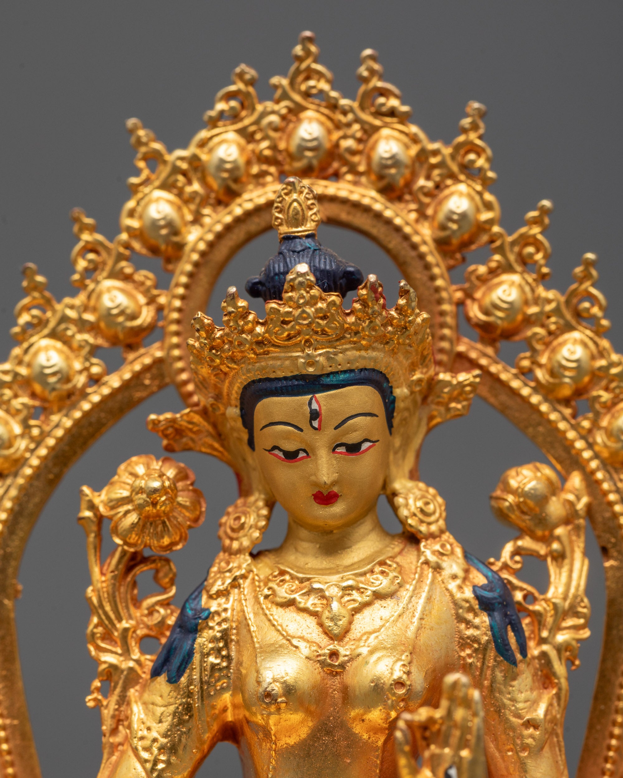 Close-up of White Tara’s compassionate face with gold-coated finish