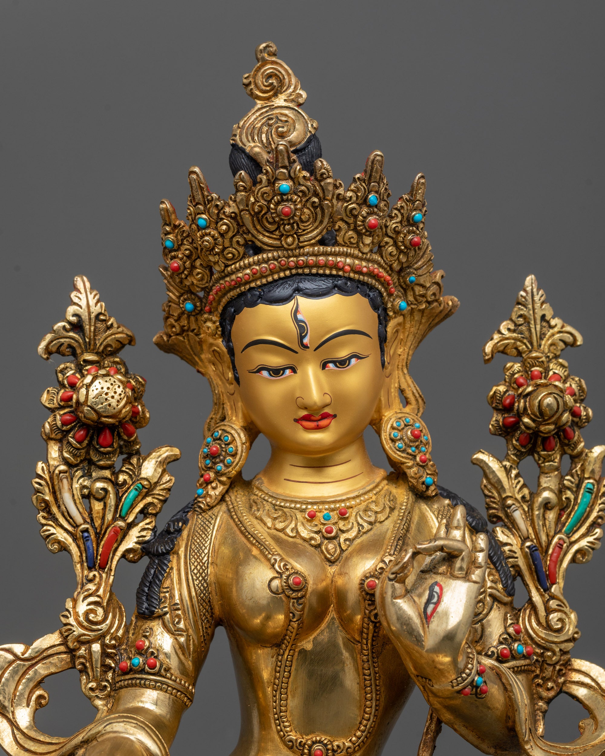 Close-up of White Tara statue showing gold-gilded face and seven seeing eyes