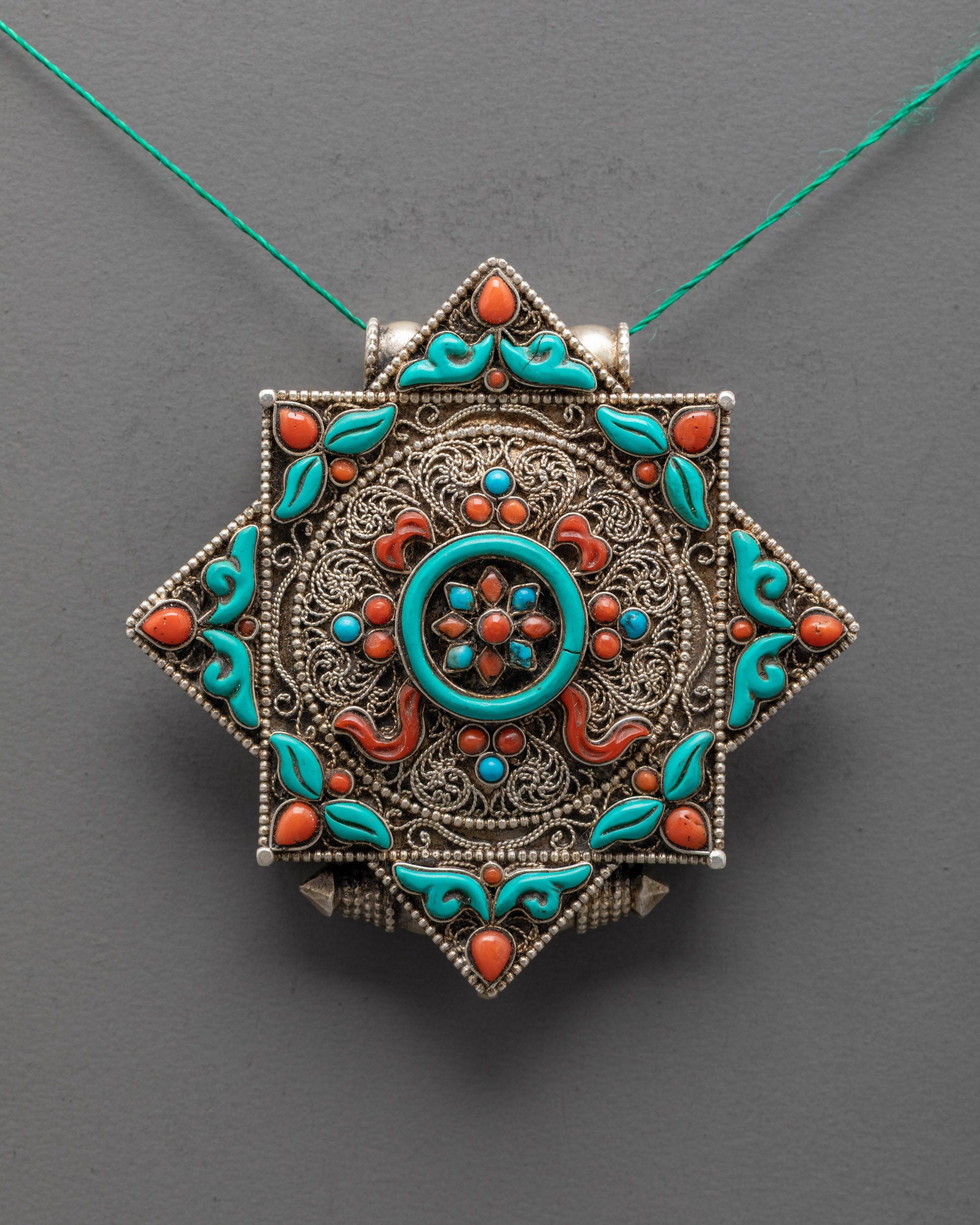 Close-up of coral and turquoise stones on handcrafted Dharma Wheel Locket