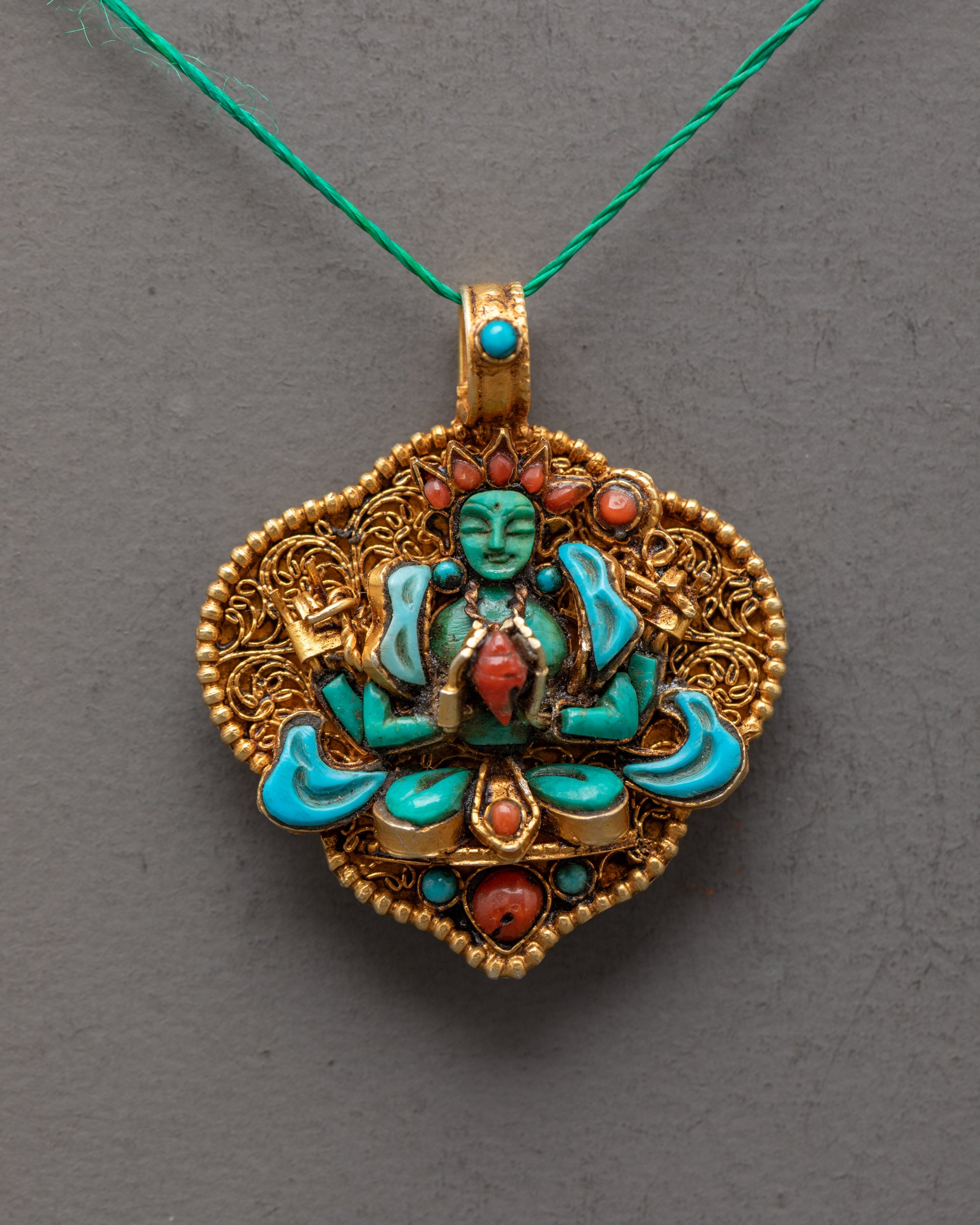 Close-up of crystal Chenrezig locket showcasing detailed turquoise robe and semi-precious stones – symbol of compassion and healing.