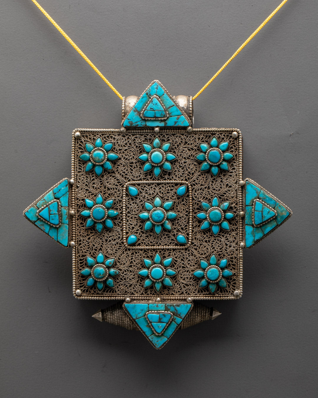 Close-up of detailed carving on Tibetan copper locket with turquoise stone