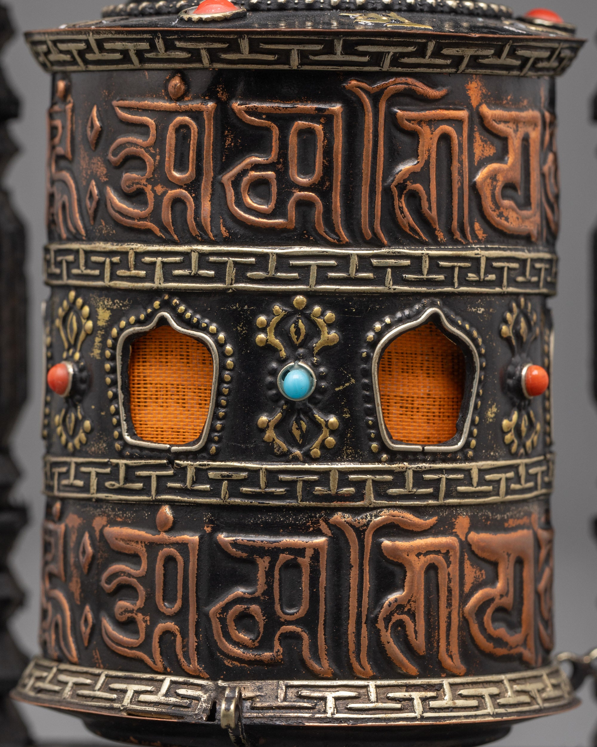 Close-up of engraved sacred mantras and bronze Dorje symbol on prayer wheel