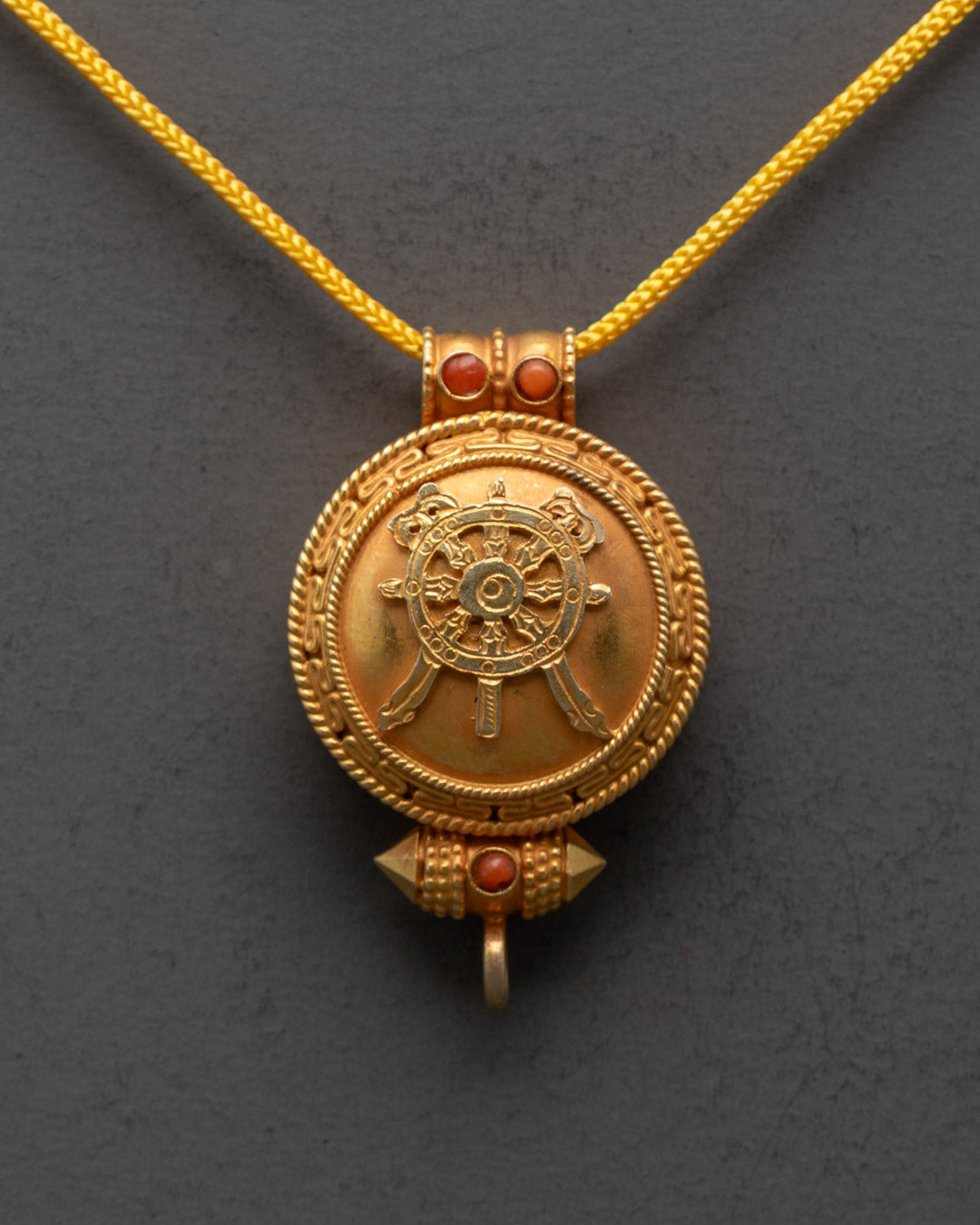 Close-up of gold-gilded Khorlo locket showing intricate carvings and stone details