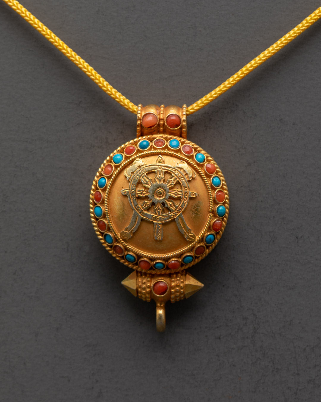 Close-up of gold-gilded Khorlo locket showing intricate carvings and semi-precious stones