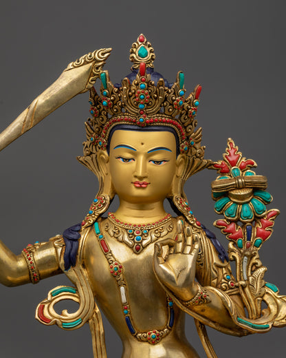Close-up of gold-gilded Manjushri face holding utpala flower and flaming sword symbolizing divine wisdom.