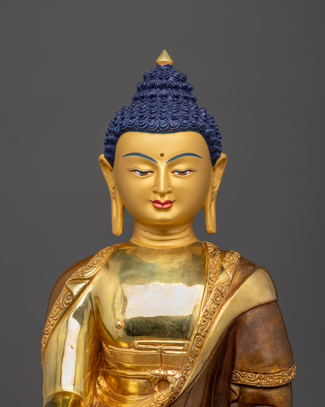 Close-up of gold-gilded face and Patra bowl of Shakyamuni Buddha statue
