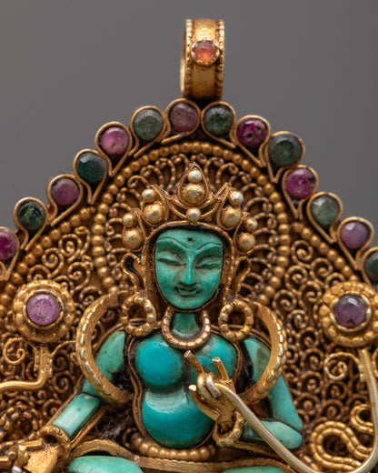 Close-up of hand-carved Green Tara holding utpala flower with coral center and gold details