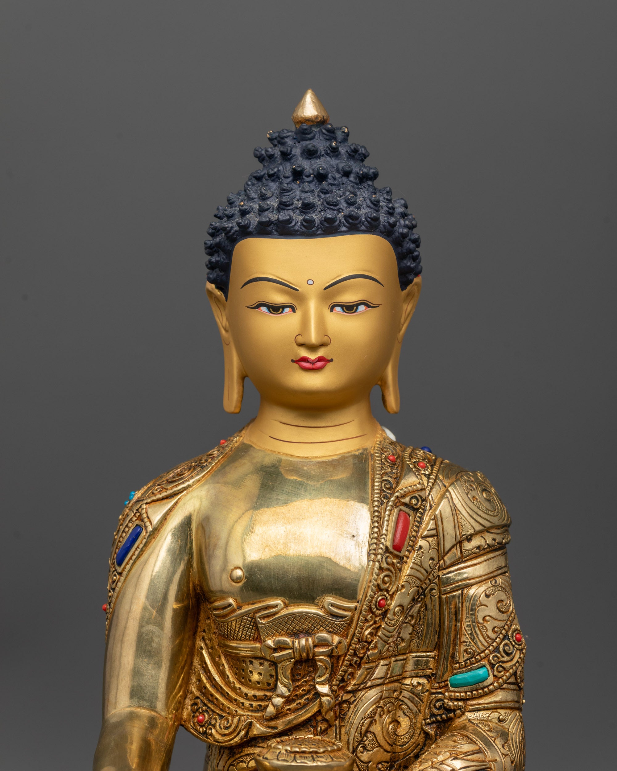 Close-up of hand-carved monk’s robe and semi-precious stones on Buddha statue