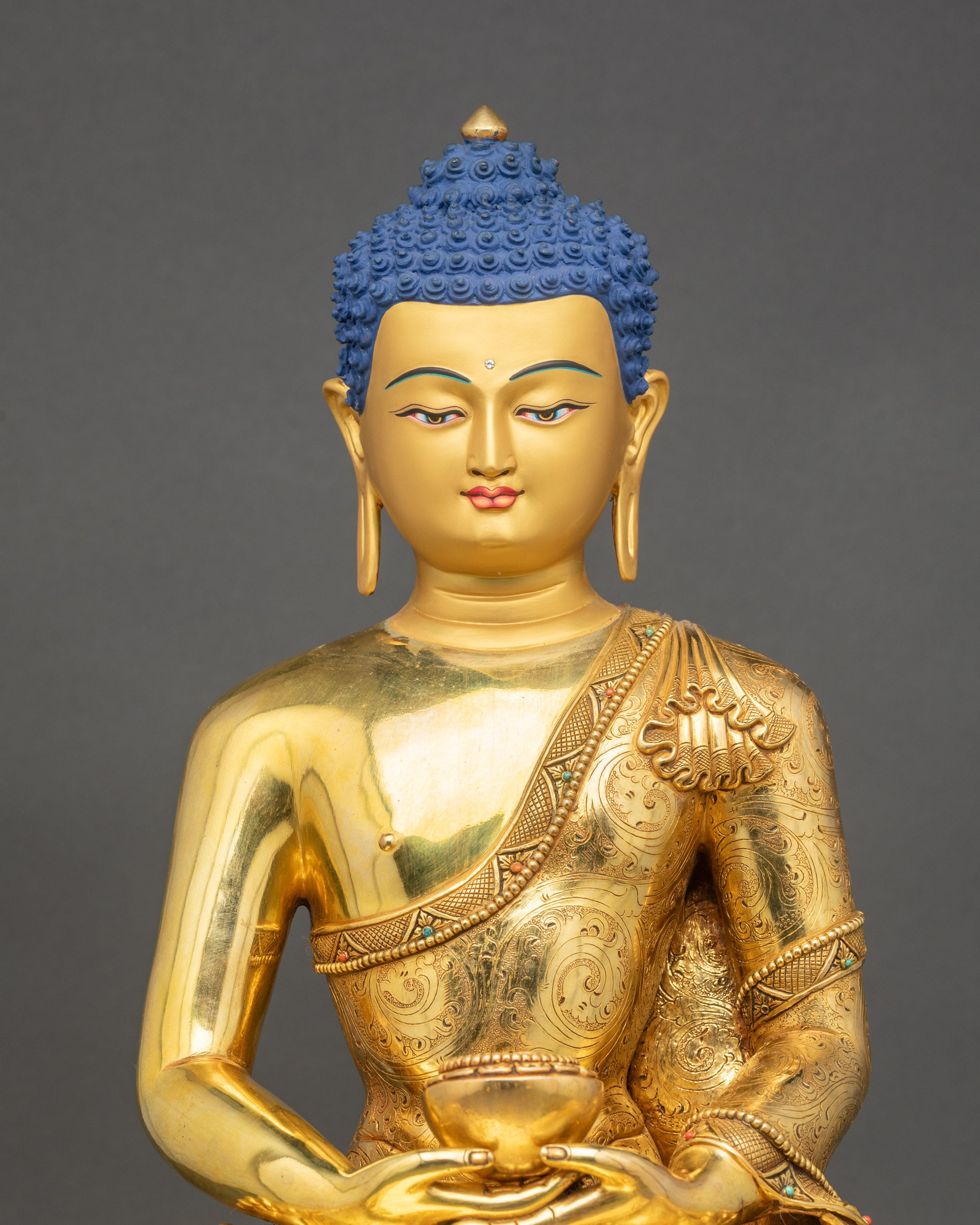 Close-up of handcrafted Amitabha Buddha showing gold fire-gilded details and robe carvings
