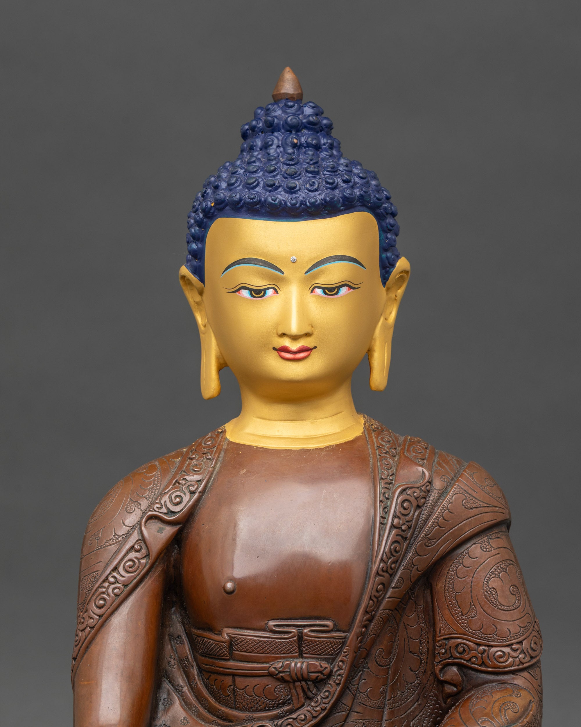 Close-up of handcrafted Nepalese Buddha statue in oxidized copper with lotus-engraved robes