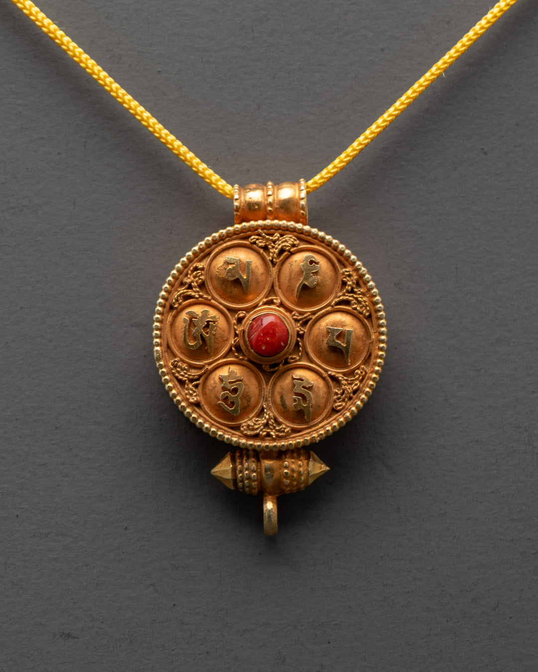 Close-up of handcrafted coral Tibetan Ghau Prayer Box Locket with filigree design