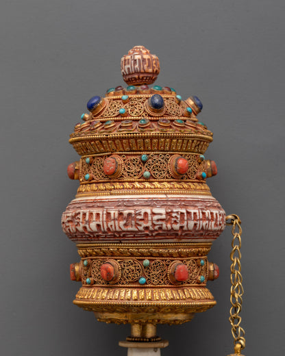 Close-up of handheld prayer wheel showing Om Mani Padme Hum engraving and vibrant stones