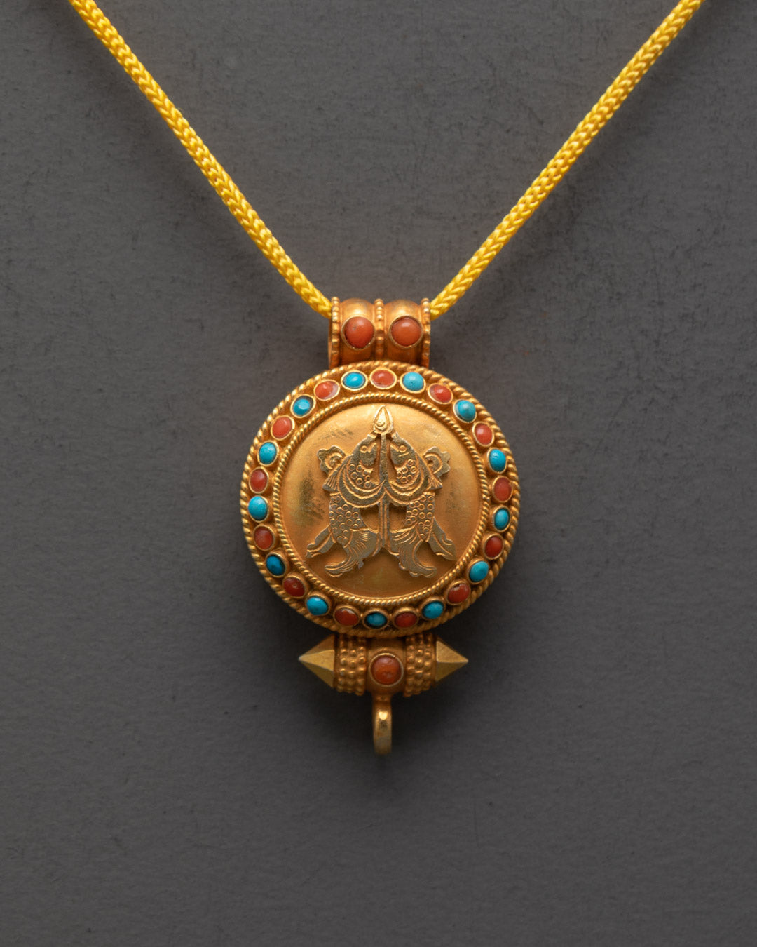Close-up of intricate Golden Fish carving on Tibetan amulet locket with sacred details
