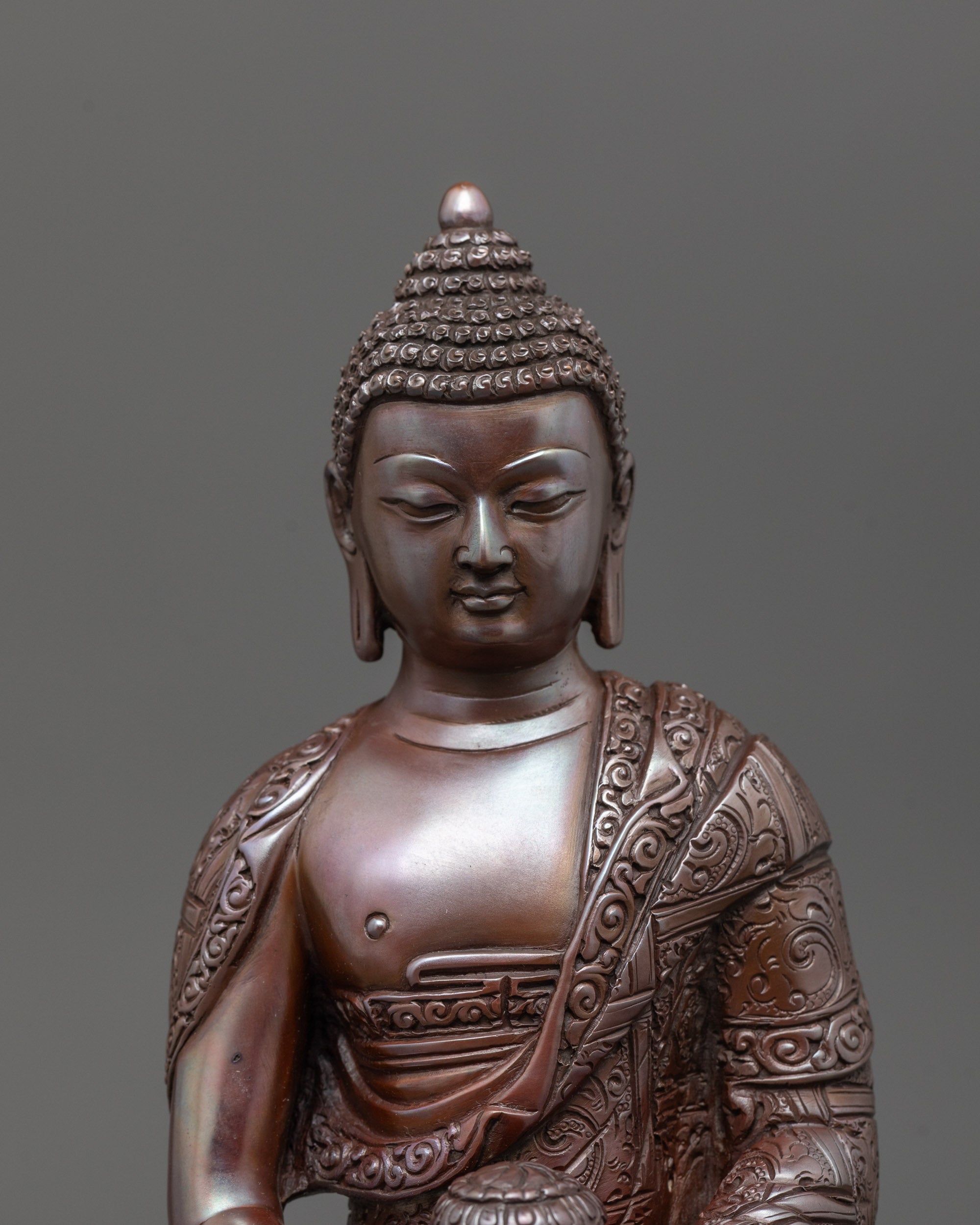 Close-up of intricate carved patterns on oxidized Amitabha Buddha holding monk’s bowl