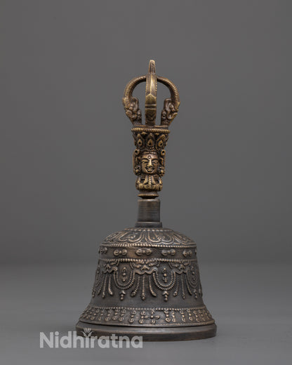 Close-up of intricate deity carving on brass handle of meditation bell
