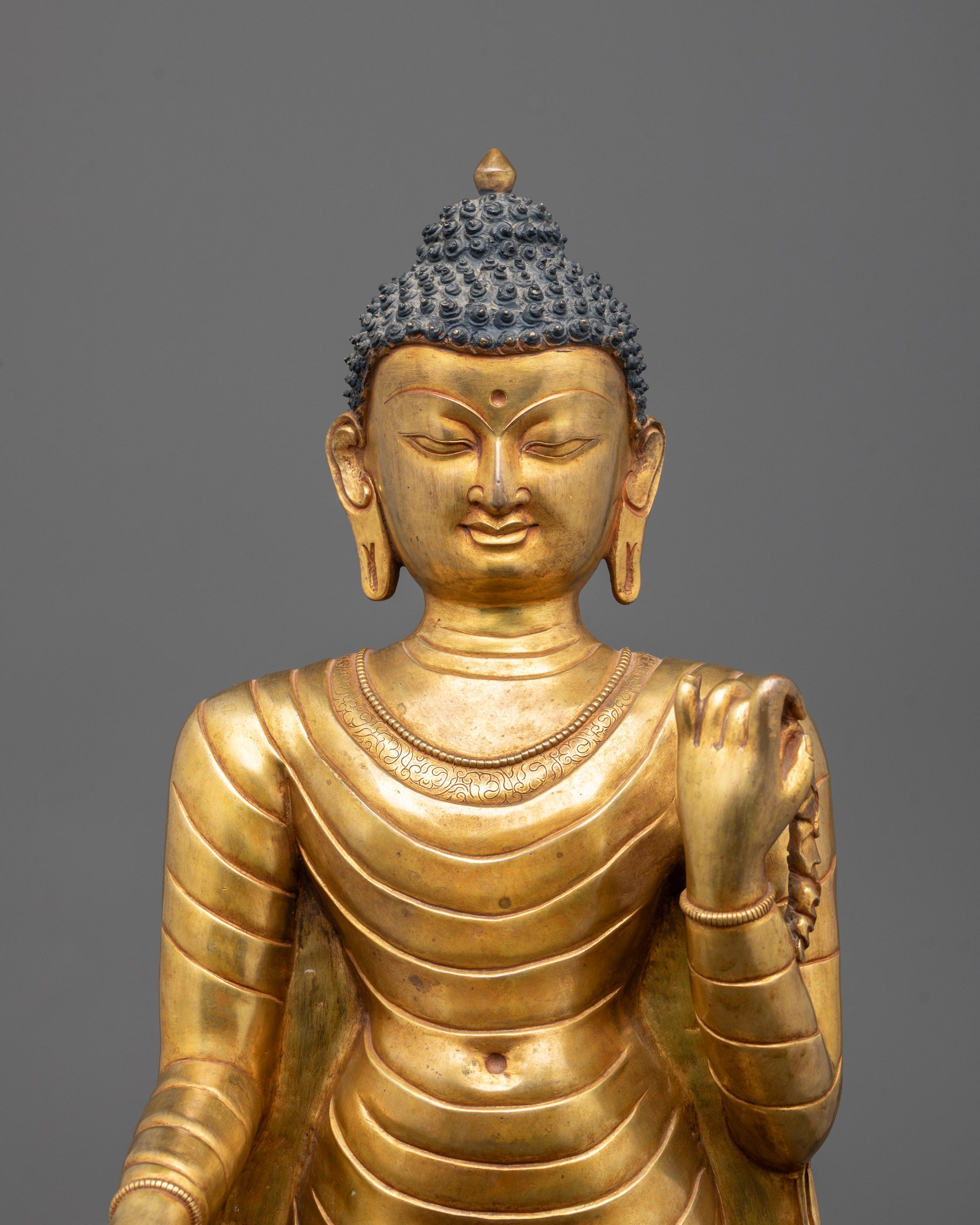 Close-up of intricate details on gold-plated Standing Buddha statue