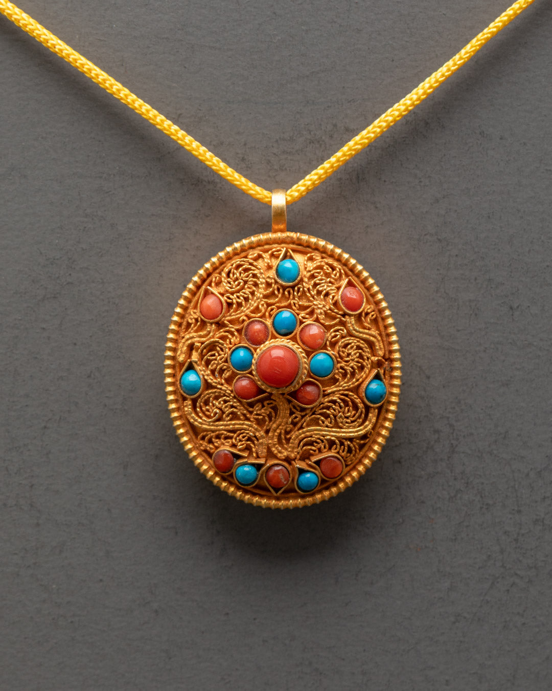 Close-up of intricate filigree design on gold-gilded Tibetan Buddhist locket pendant