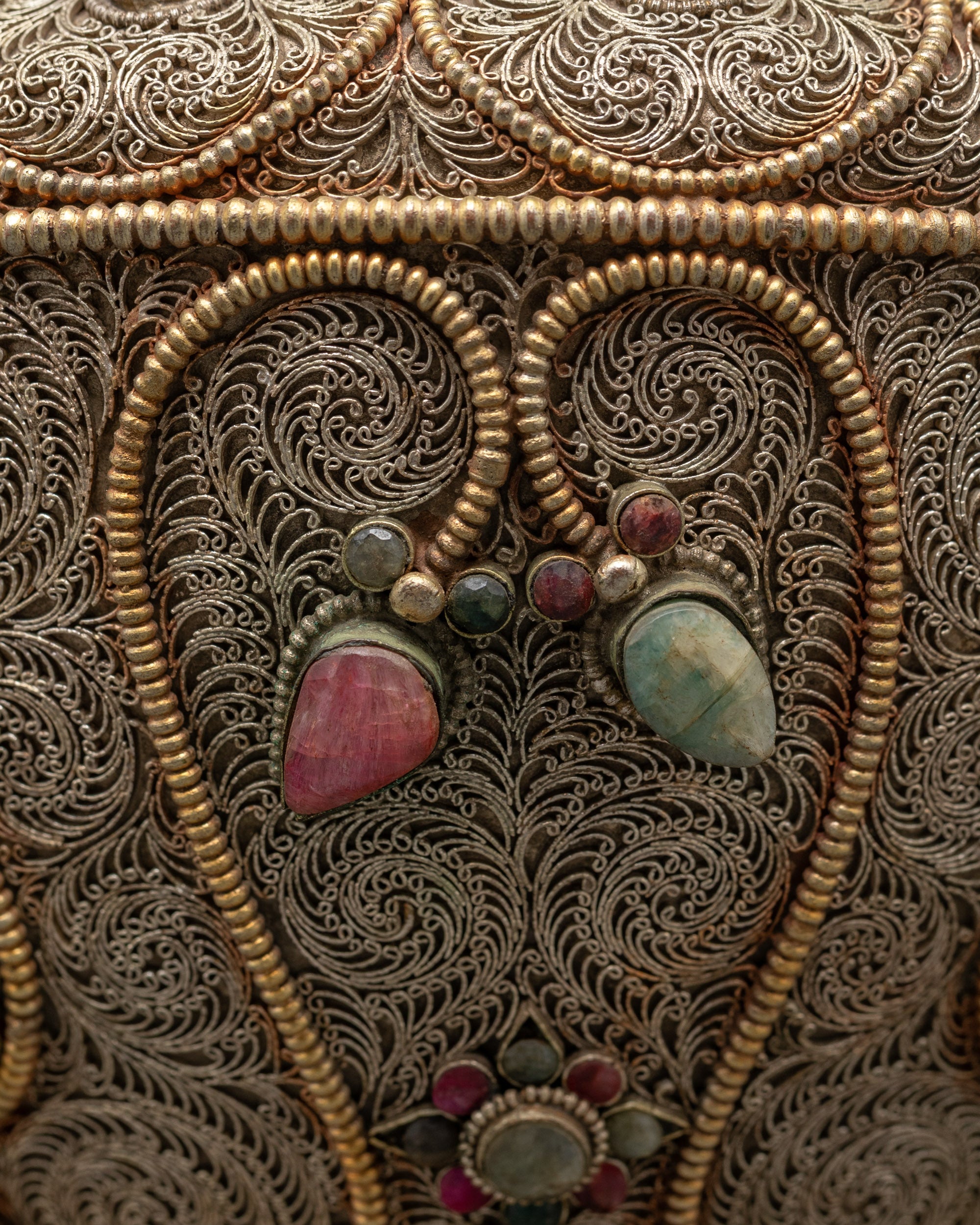 Close-up of intricate silver filigree and deity figures on Nepalese handcrafted rice pot

