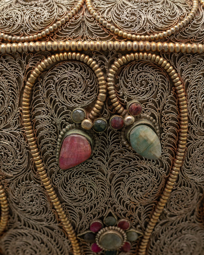 Close-up of intricate silver filigree and deity figures on Nepalese handcrafted rice pot

