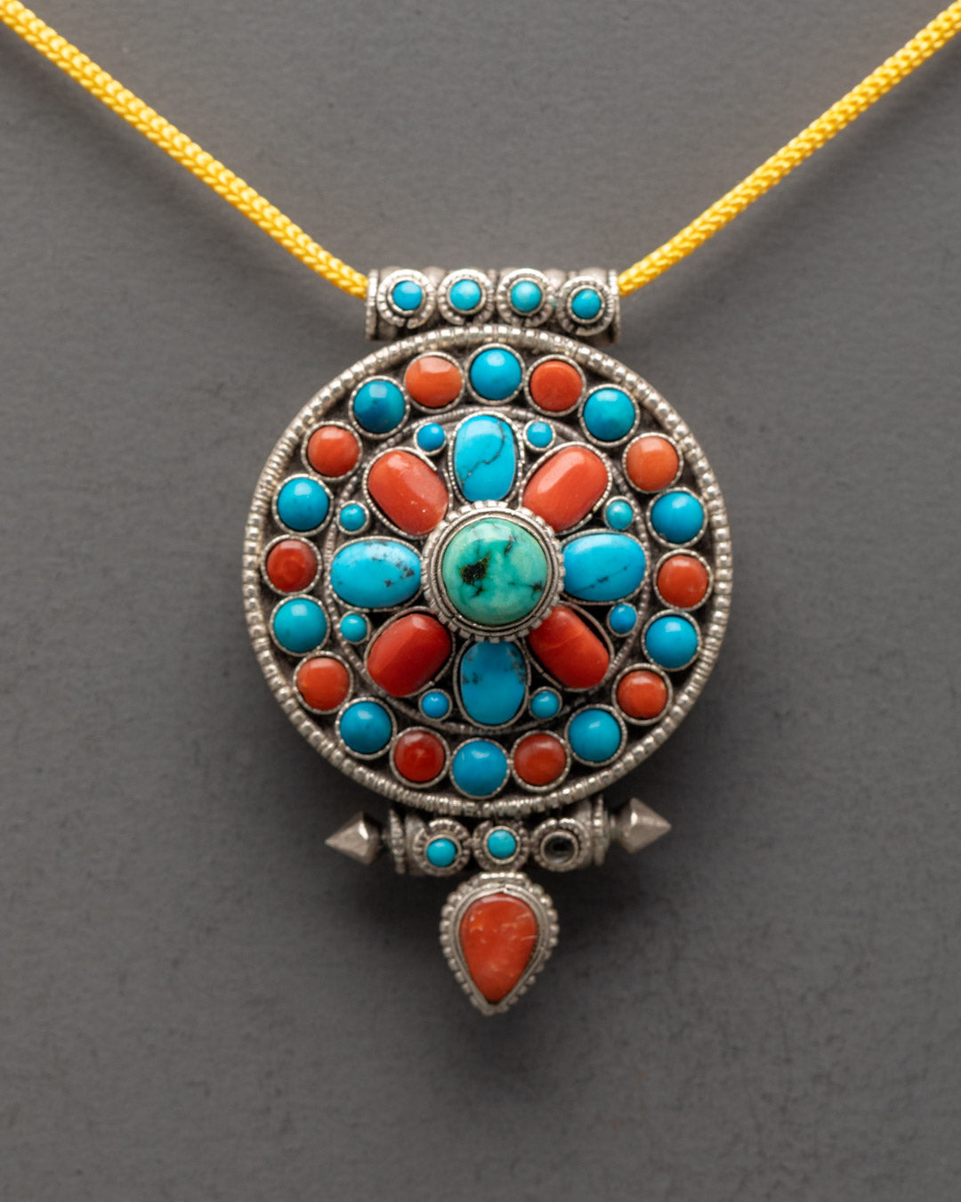 Close-up of intricately carved silver Tibetan pendant showcasing artisan craftsmanship
