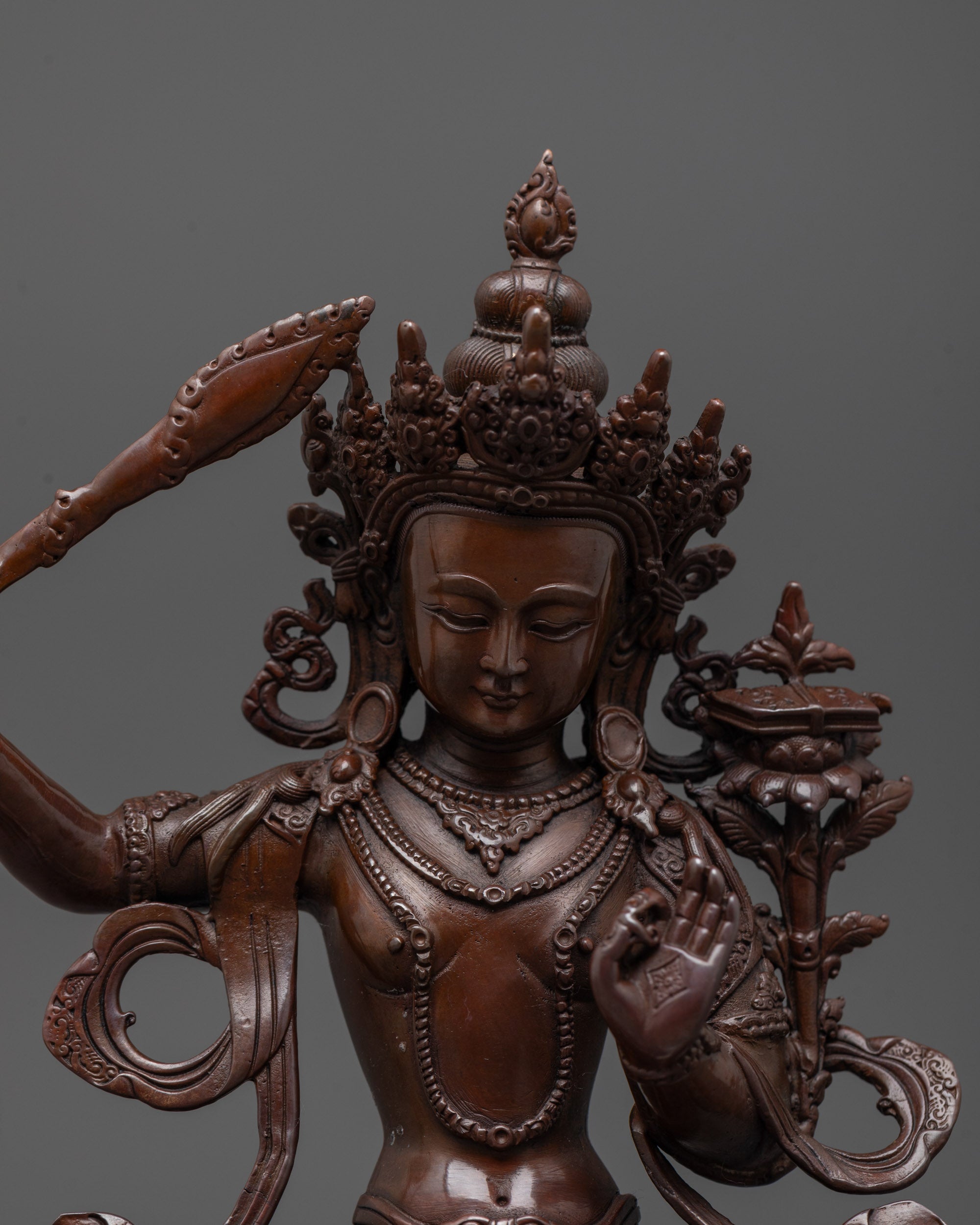Close-up of oxidized copper Manjushri statue highlighting fine carvings and rich electroplated tone
