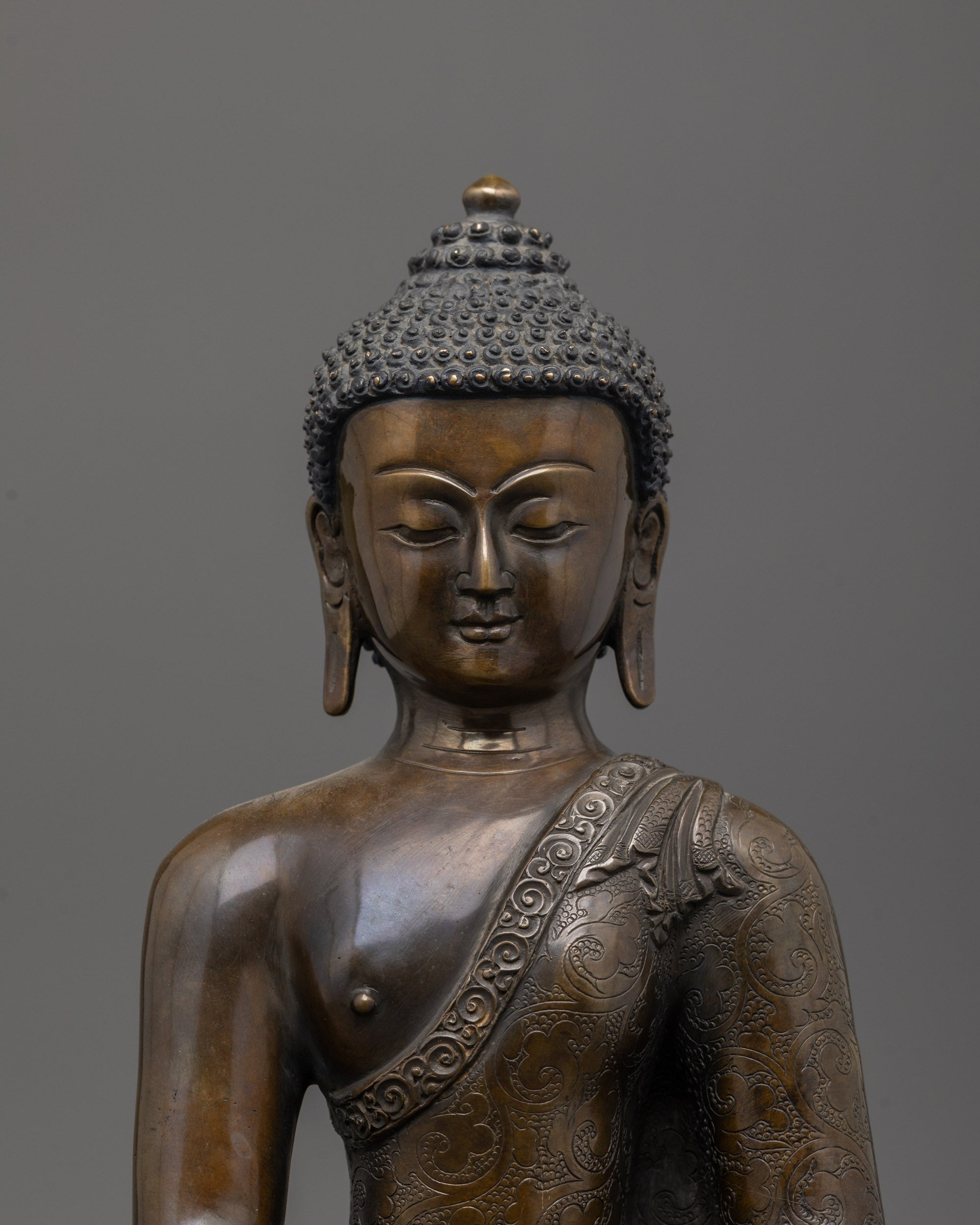 Close-up of oxidized copper face and intricate carvings on Shakyamuni Buddha statue