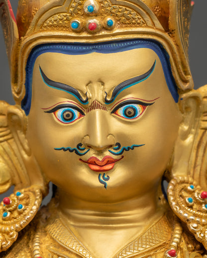 Close-up of serene Guru Rinpoche face, hand-painted details on gold-gilded Tibetan Buddhist statue