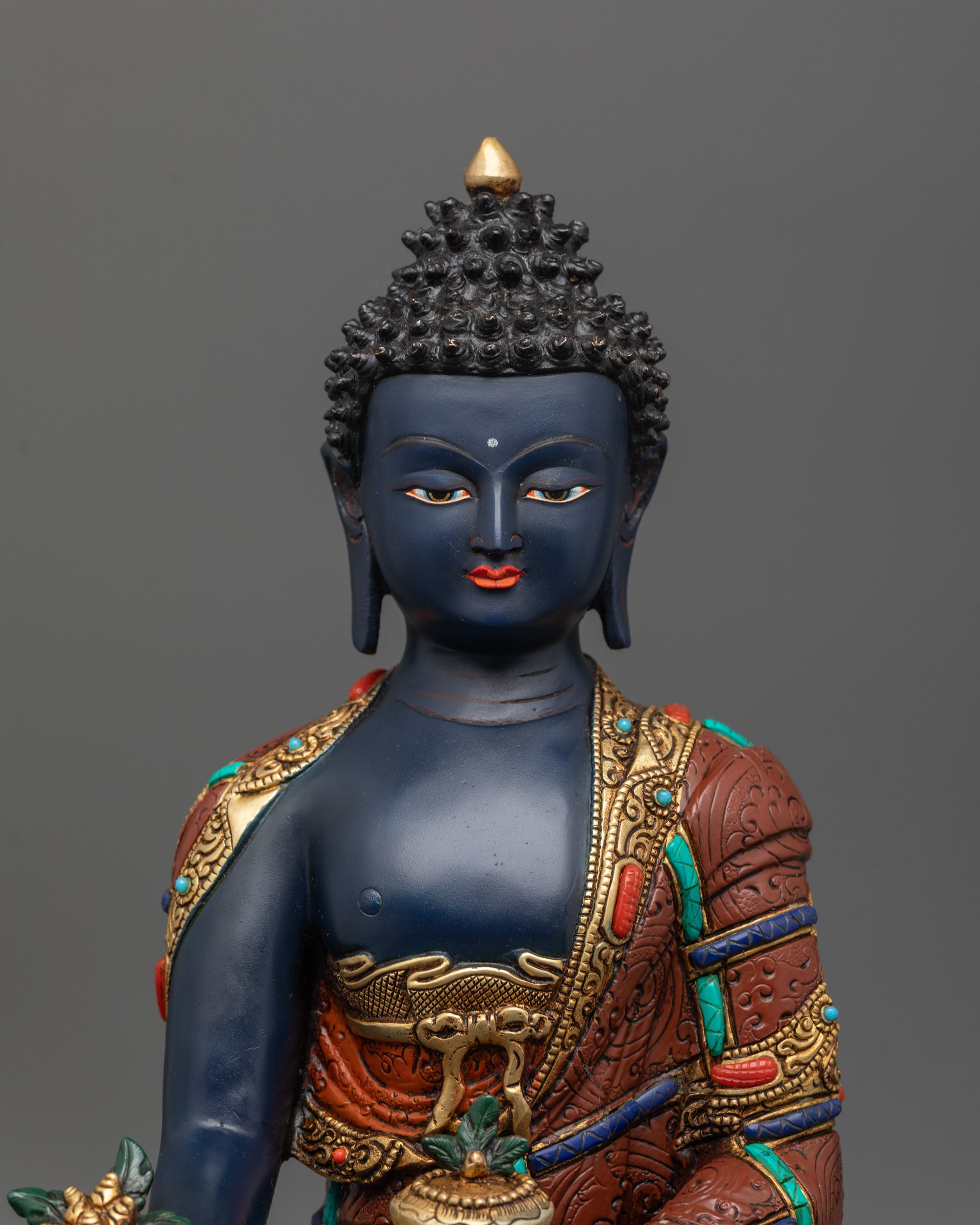 Close-up of serene face of Medicine Buddha with gold-plated details