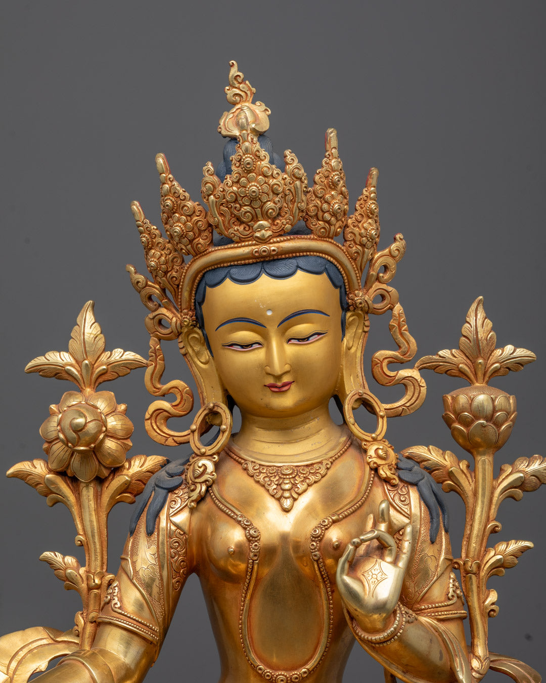 Close-up of serene gold-gilded face and ornate five-jeweled crown of Green Tara