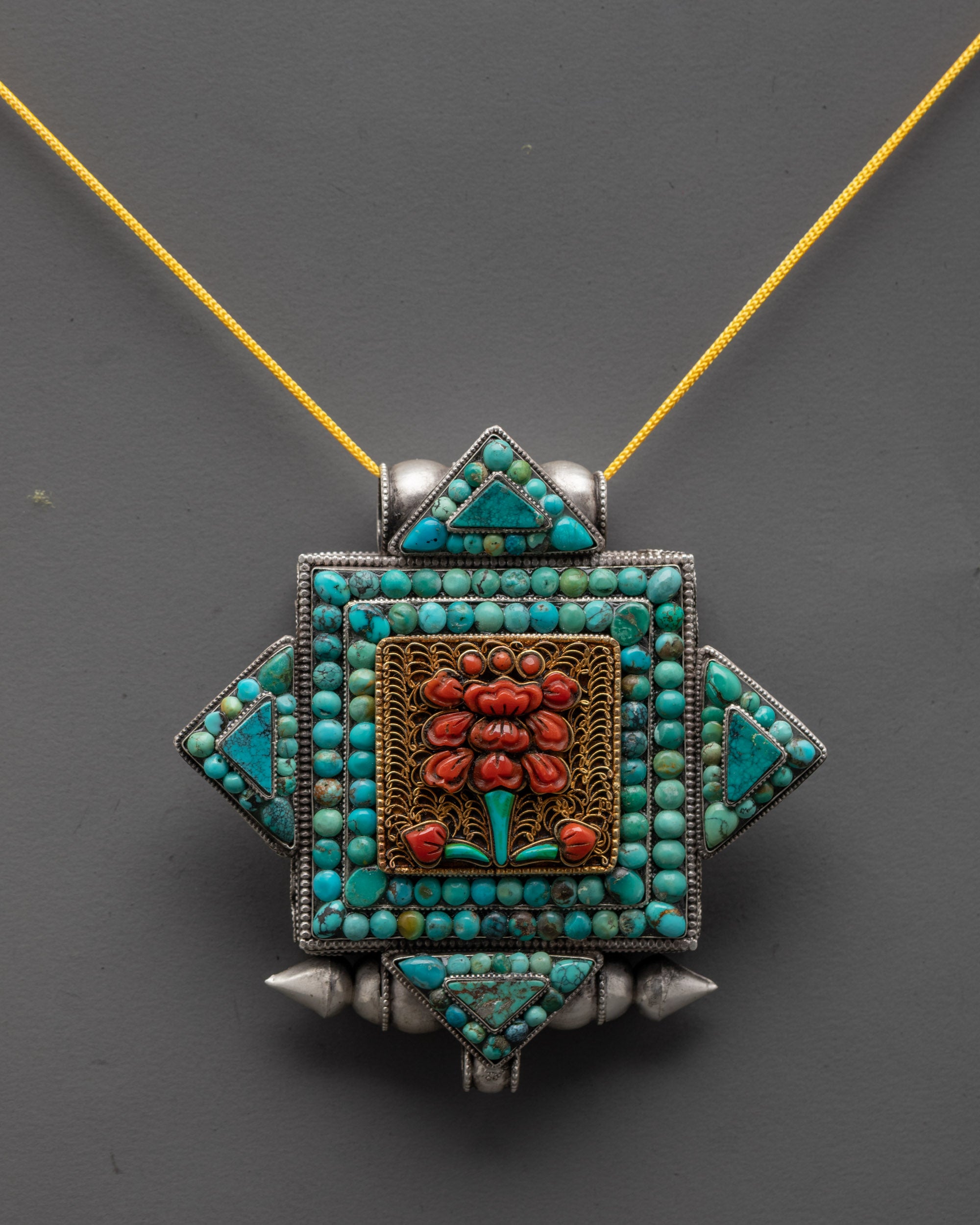Close-up of silver flower locket pendant showing gold-plated filigree and flower symbol