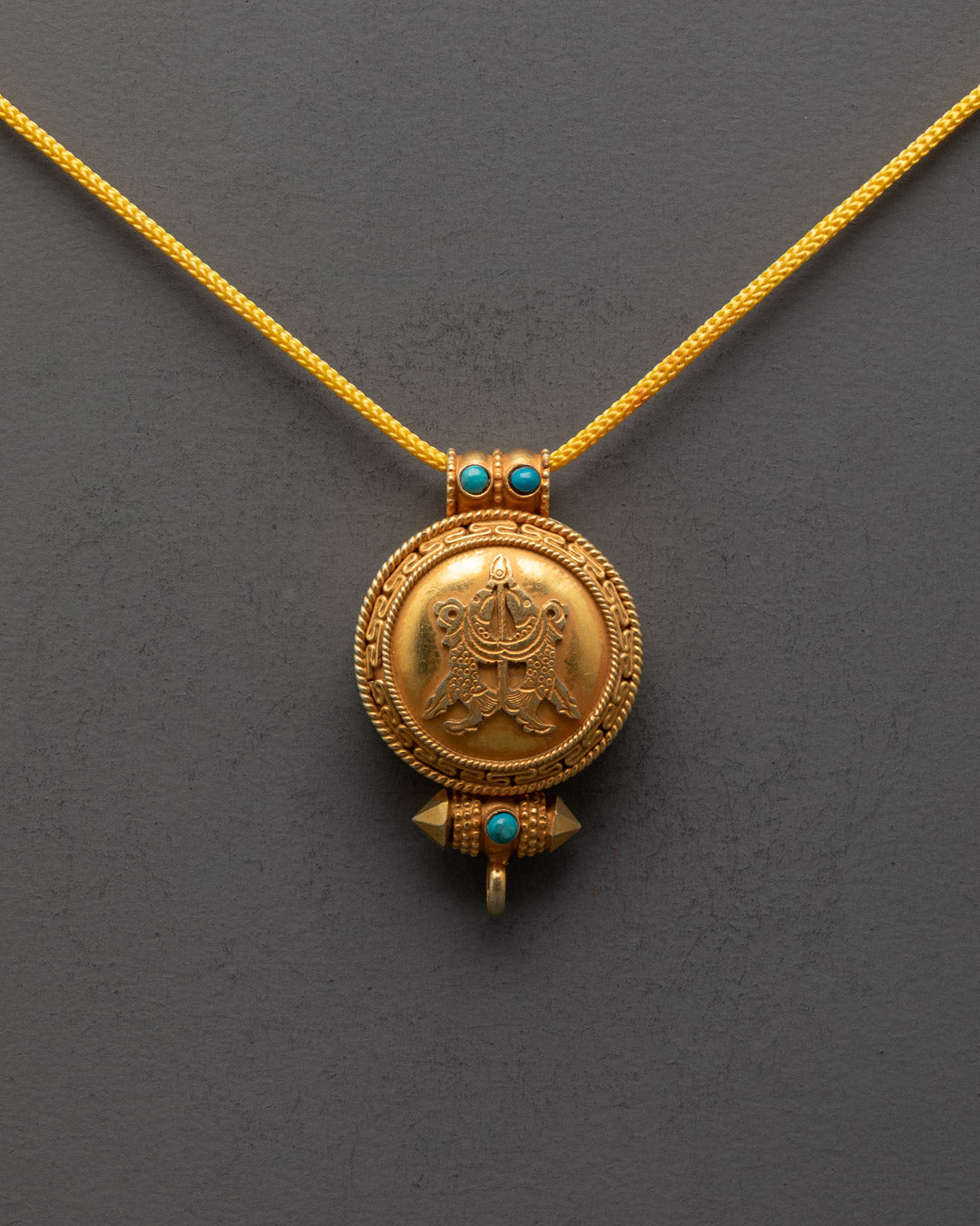 Close-up of symbolic fish motif on handcrafted Buddhist Ghau locket with stones