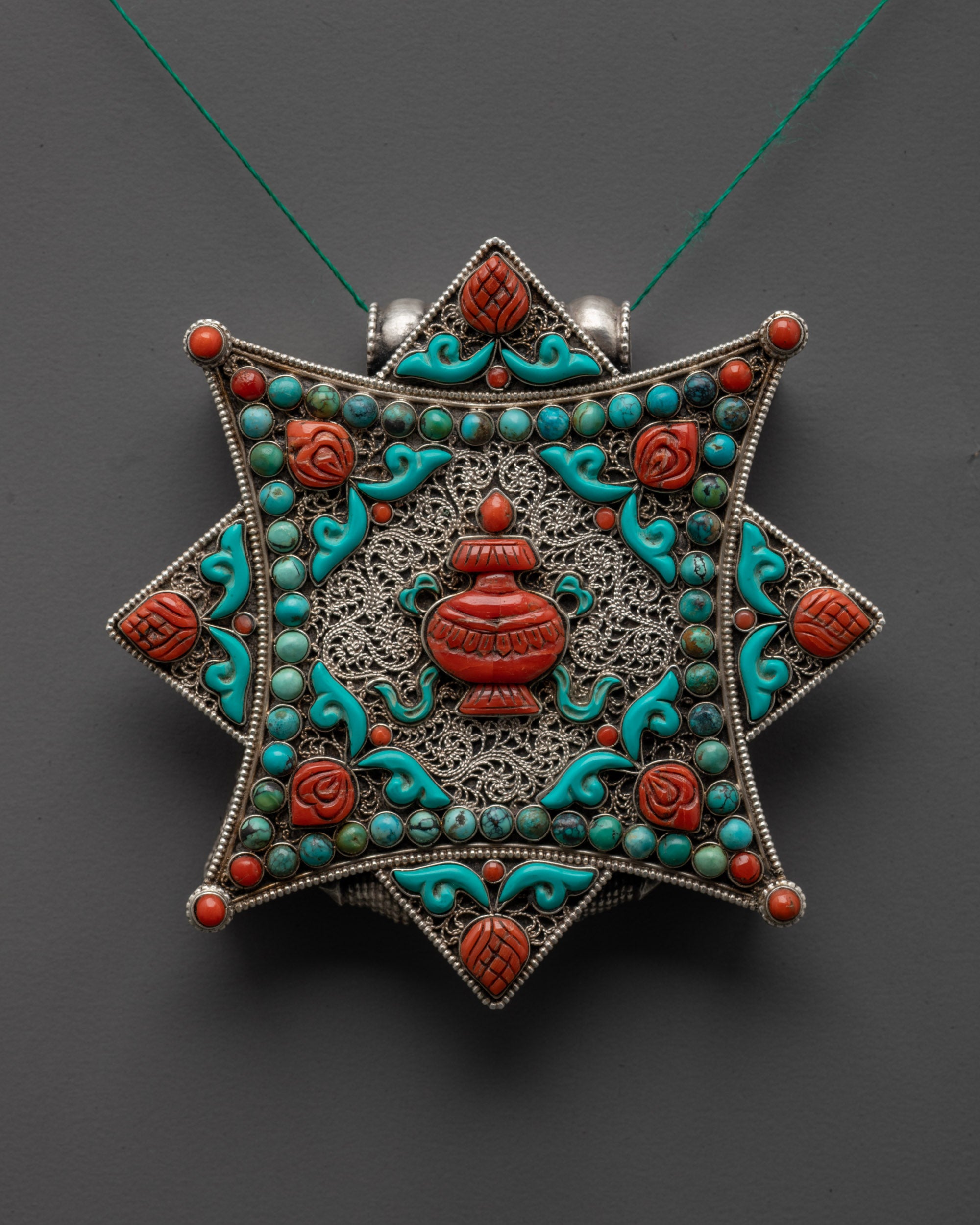 Close-up of turquoise Kalash vase symbol with coral and turquoise stone details