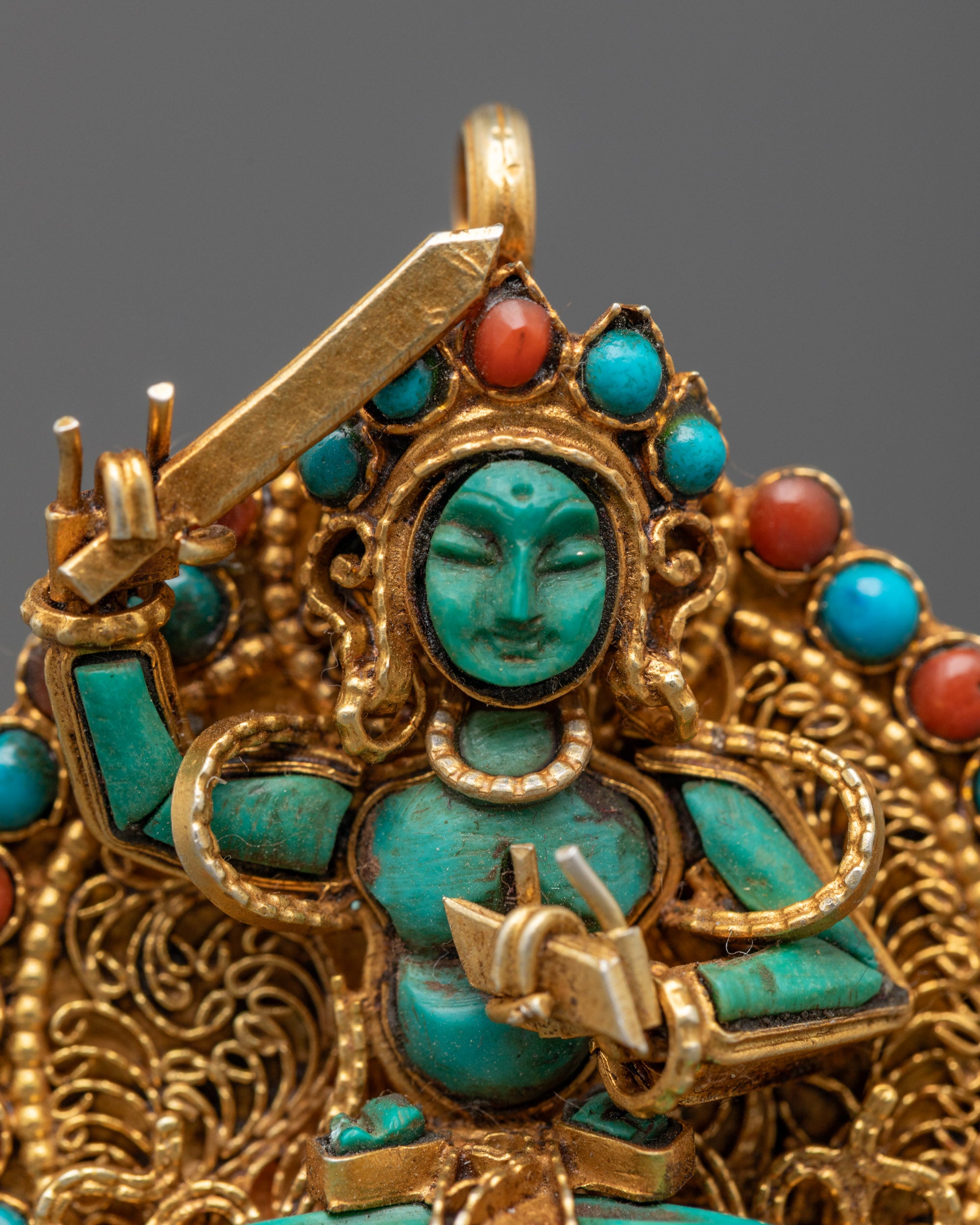 Close-up of turquoise Manjushri locket showing gold filigree and semi-precious stones detail
