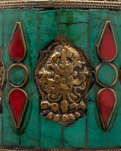 Close-up of turquoise and coral inlays on copper Auspicious Prayer Wheel with detailed mantra engravings