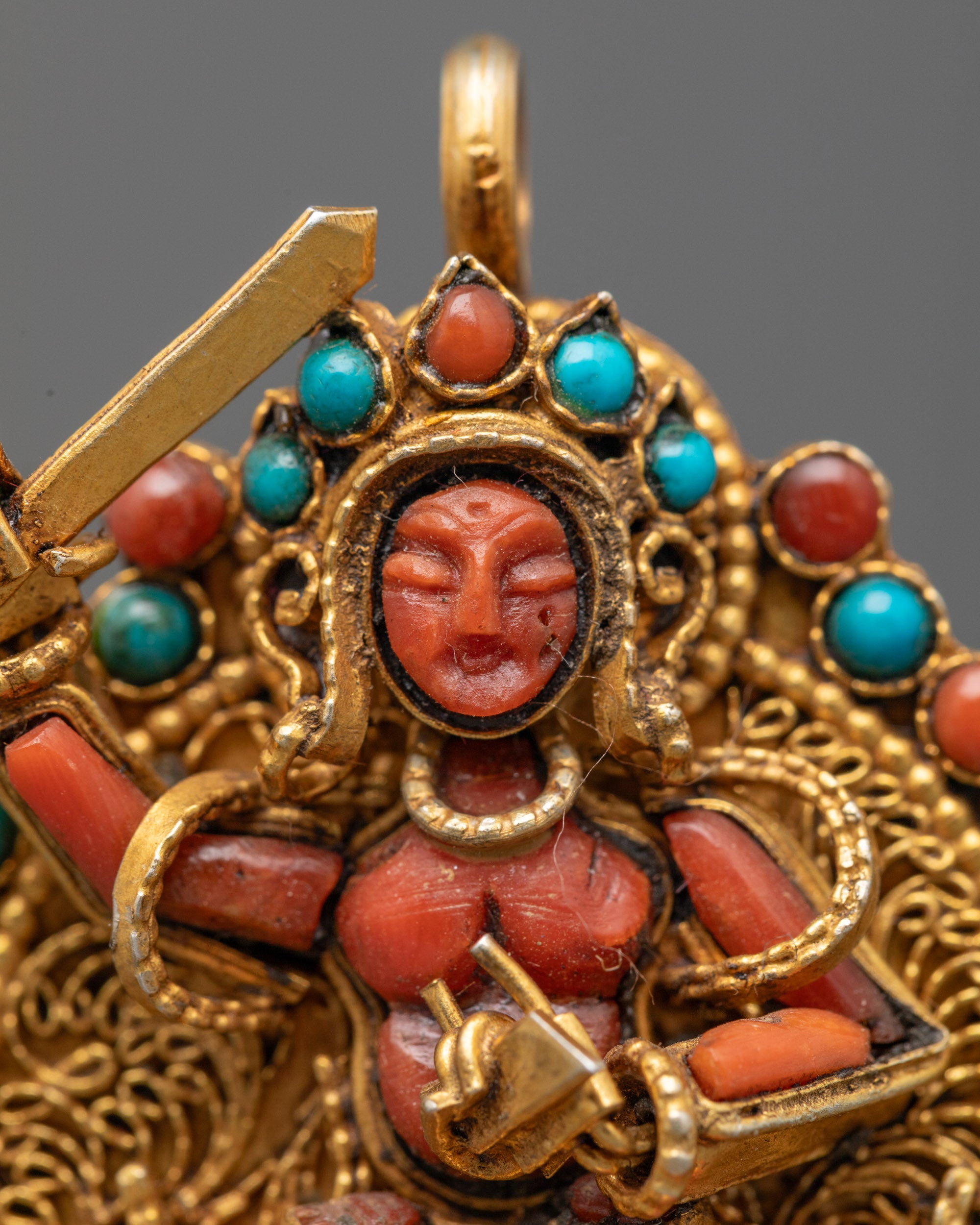 Close-up of vibrant Coral Manjushri centerpiece on gold-gilded filigree locket from Patan, Nepal