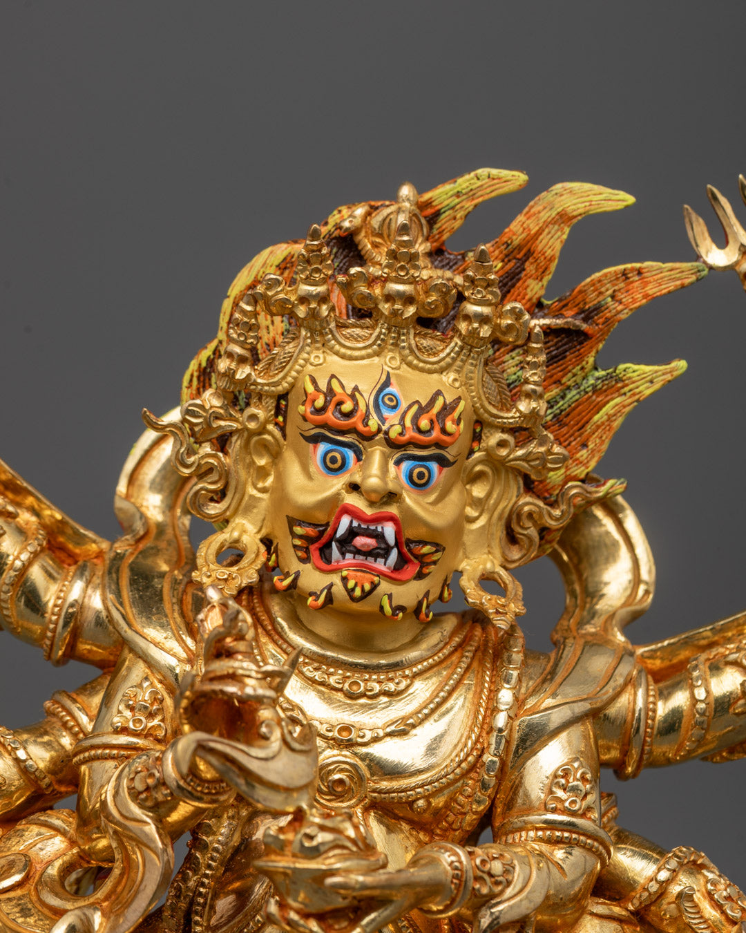 Close-up of wrathful face and six arms of Mahakala holding symbolic ritual objects