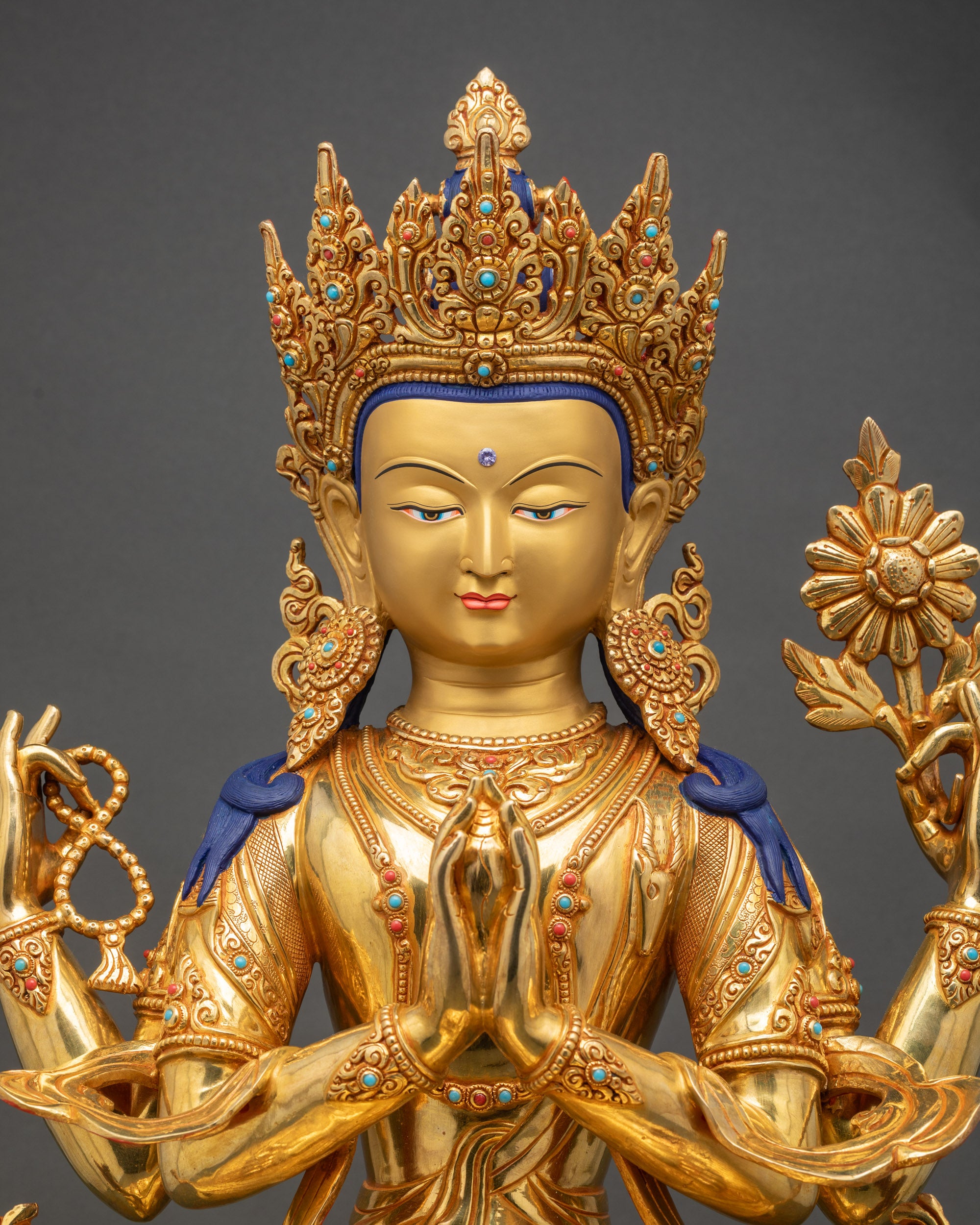 Close-up showing intricate 3D carvings, gold-painted face, and jewelry details on Chenrezig