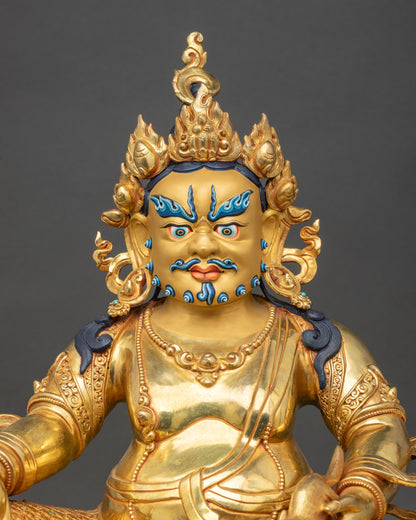 Close-up view of Dzambhala statue showing gold crown, jewelry, and rich ritual details