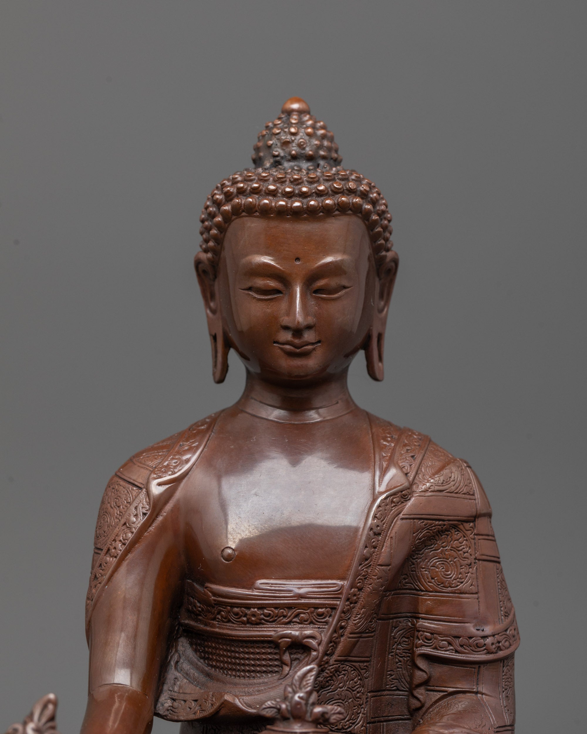 Close-up view of Medicine Buddha’s peaceful face and detailed hand holding healing herb