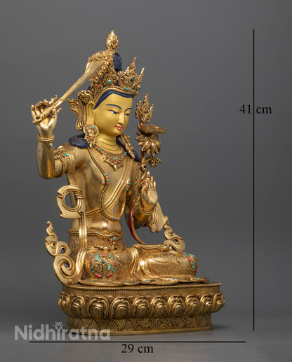 Close-up view of the Manjushri statue showing the 24k gold gilded copper craftsmanship, highlighting the serene expression and fine details.