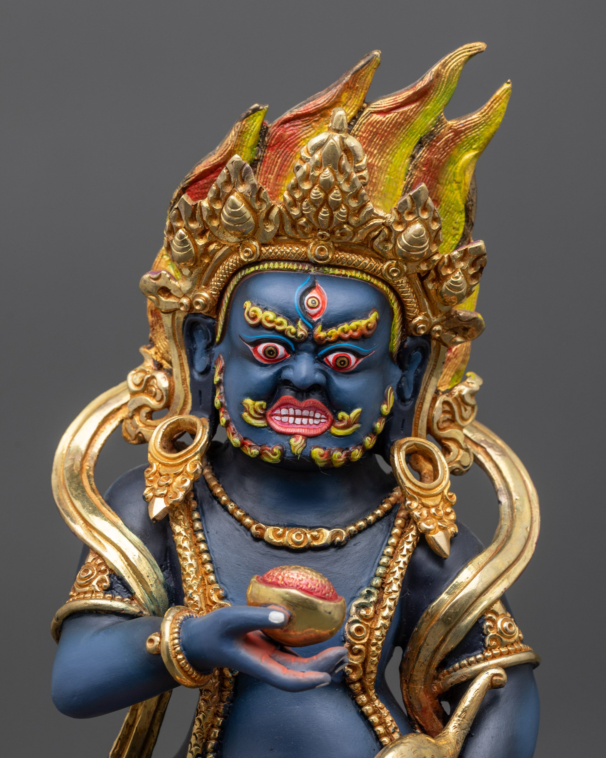 Close up Black Dzambhala sculpture showing jewel-spitting mongoose and skull cup details