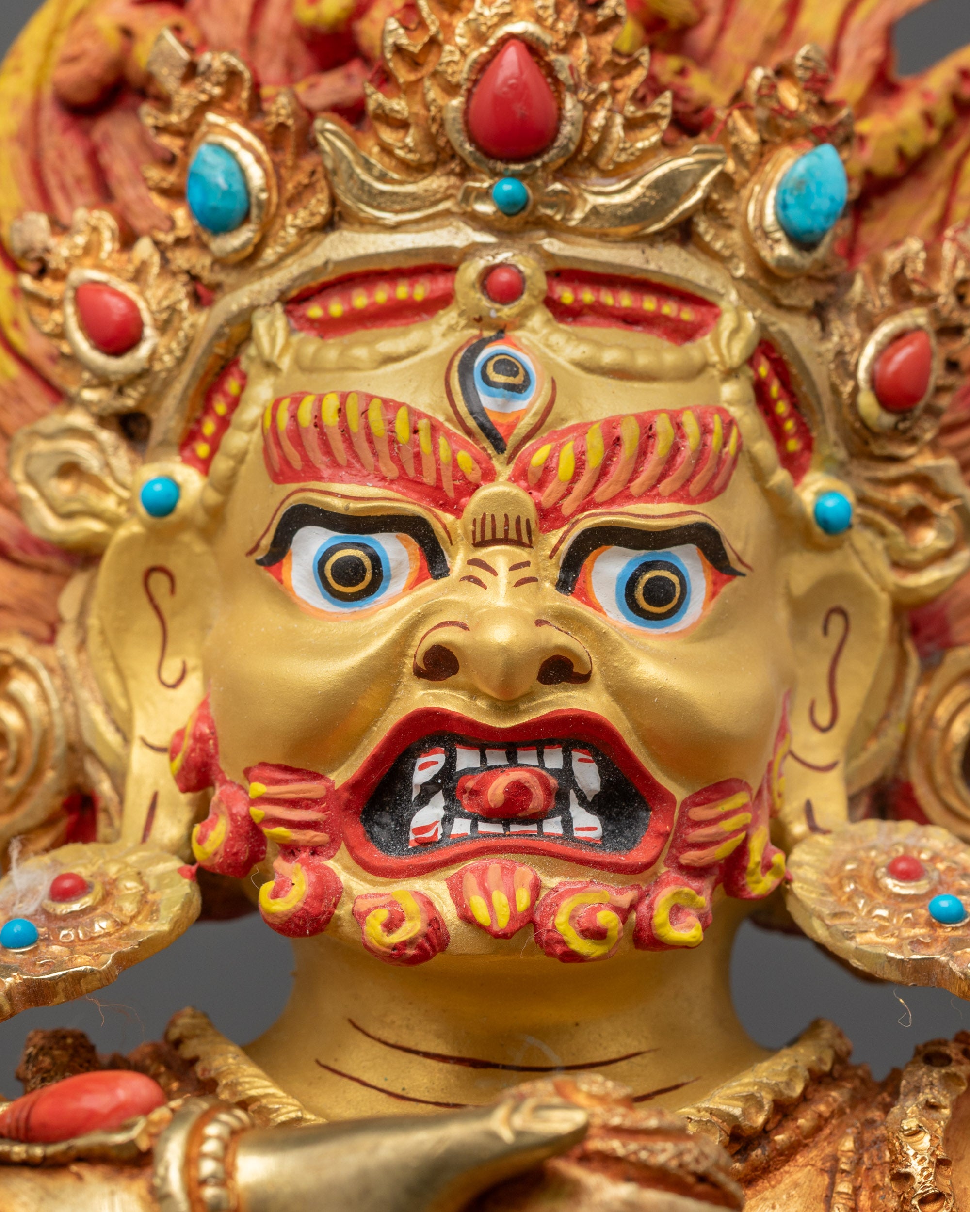 Close up Black Dzambhala showing gold-gilded face, third eye, and jeweled mongoose