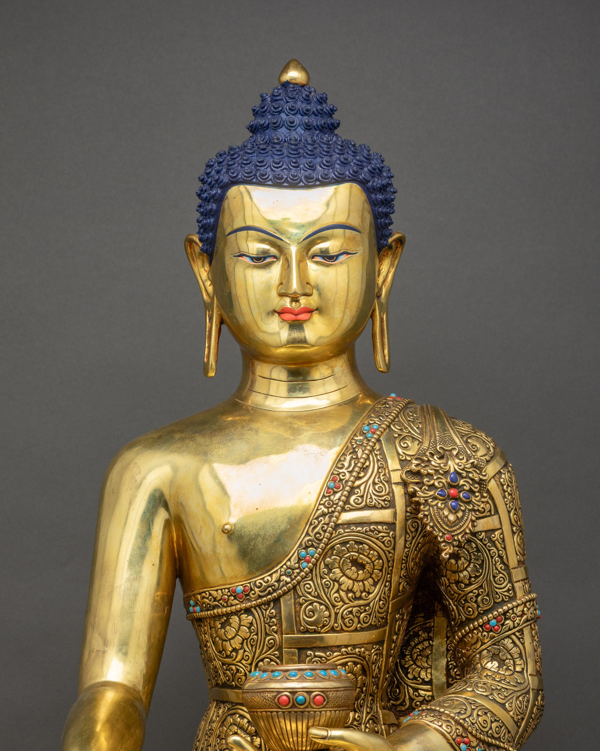Close up Buddha Shakyamuni Statue showing floral motifs, filigree, and reflective copper
