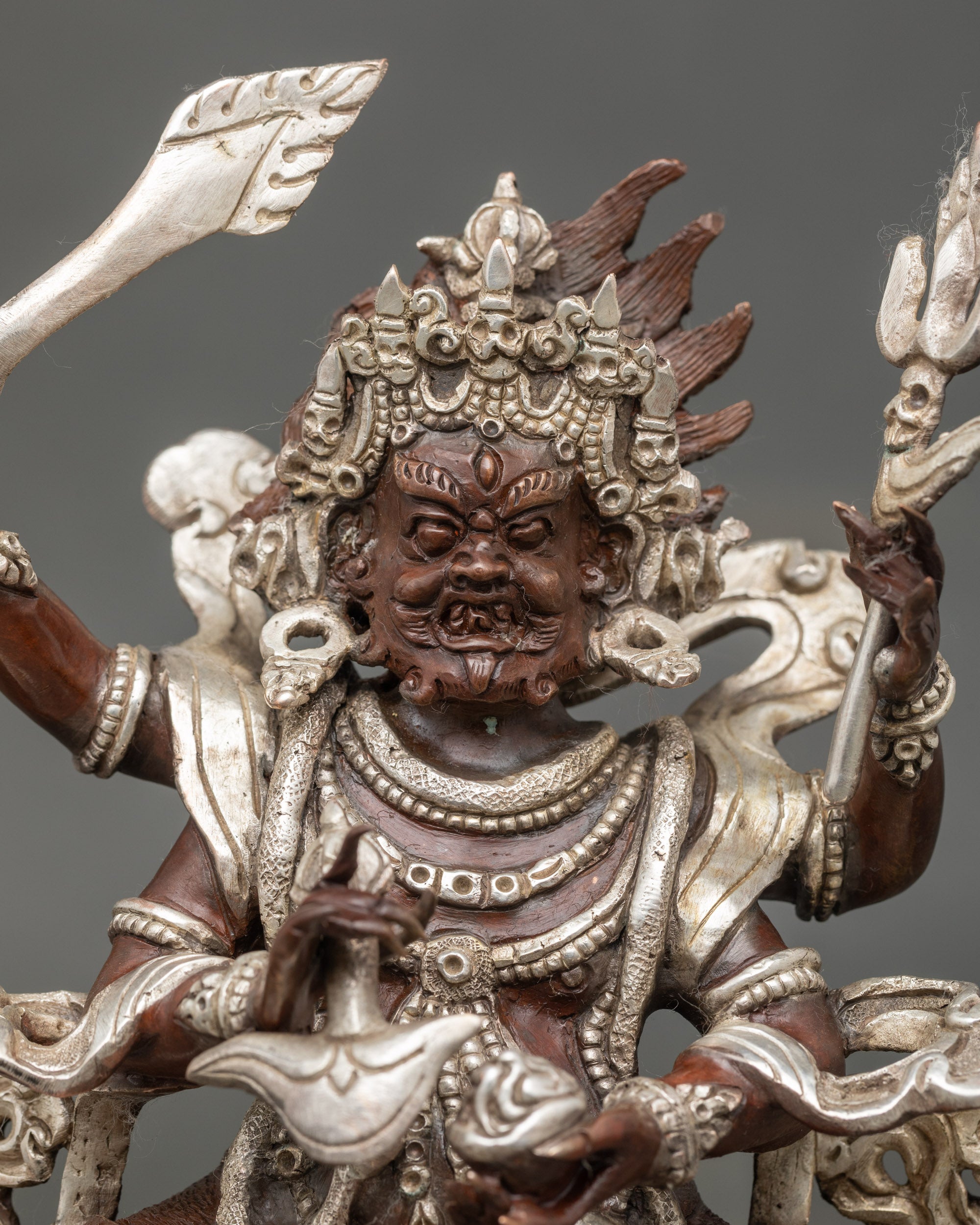 Close up Chaturbhuja Mahakala wrathful face showing silver-plated accents and detailed carving