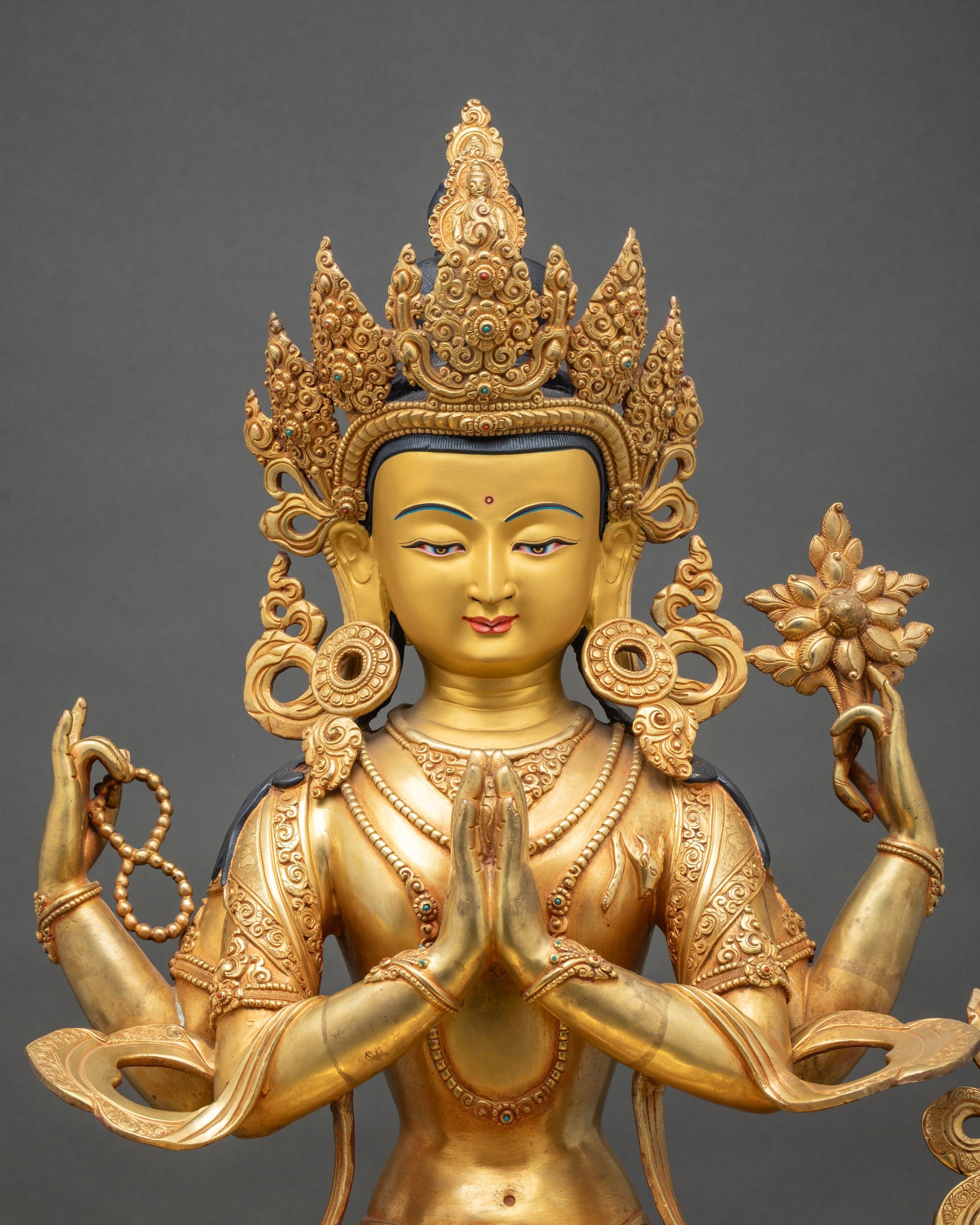 Close up Chenrezig face with gold-painted features, crown, and intricate carving