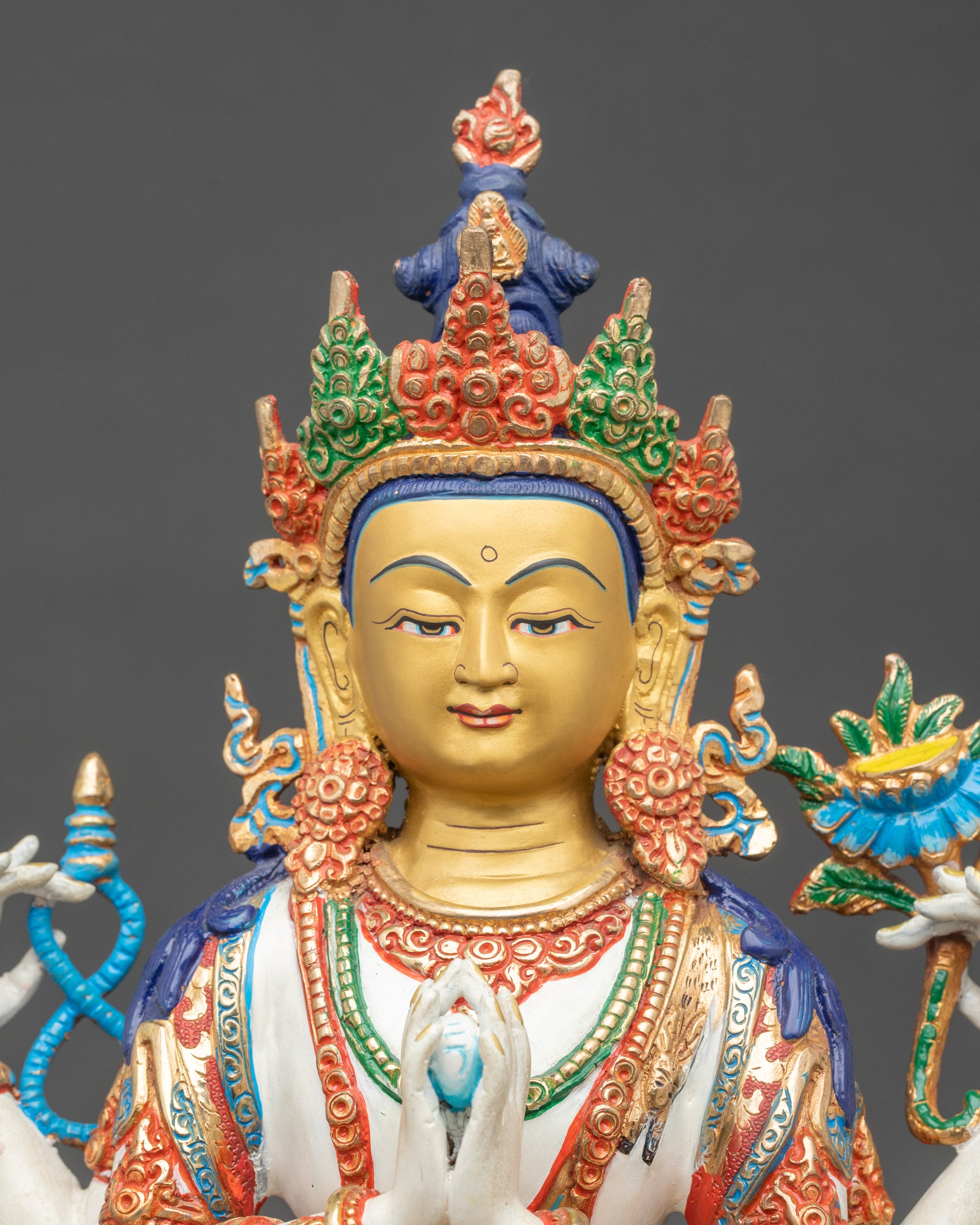 Close up Chenrezig face with serene expression and gold-painted detailing